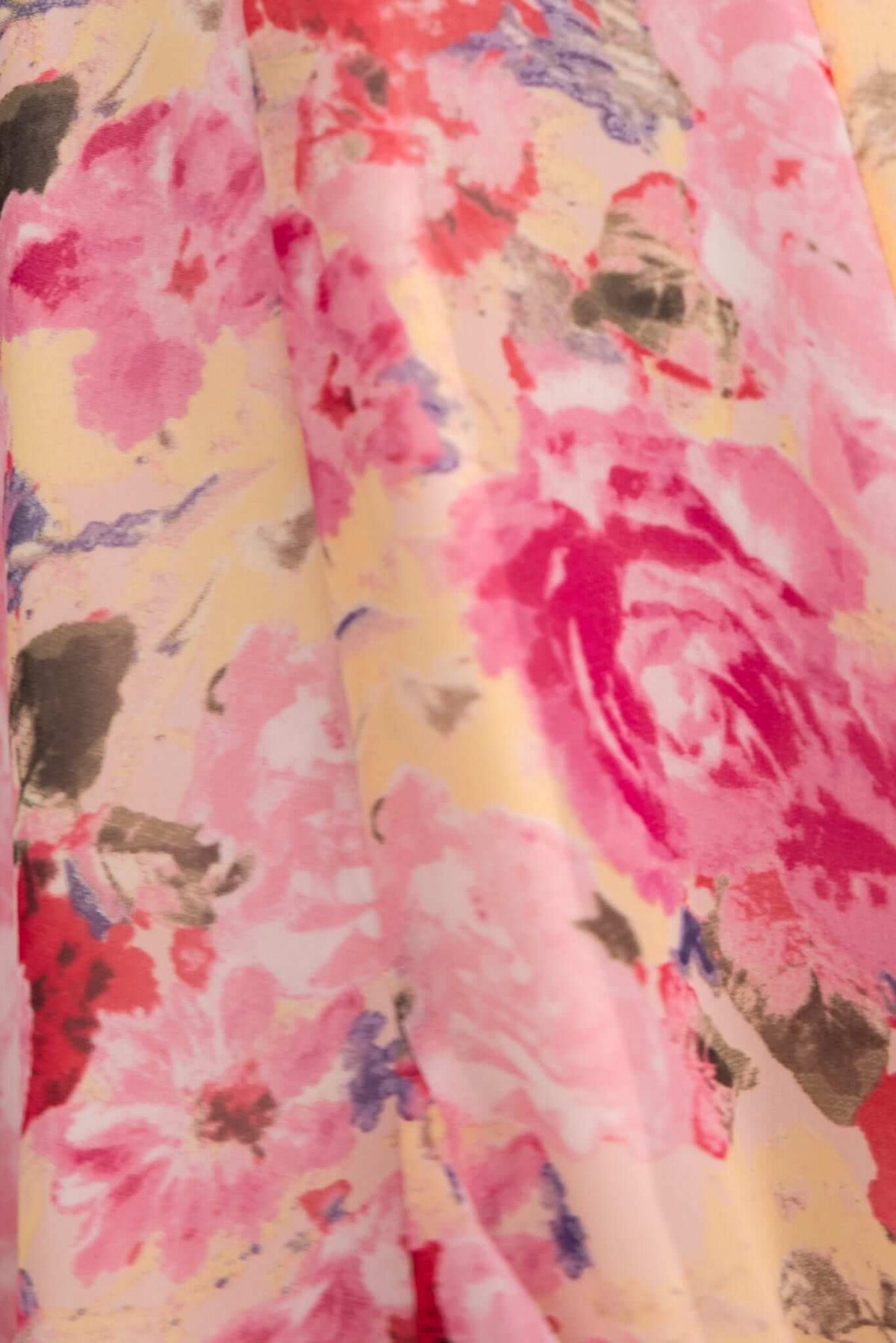 Close-up of floral chiffon fabric featuring pink and yellow flowers, ideal for a romantic dress design.