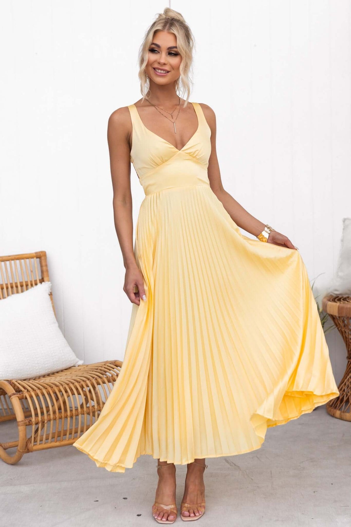 Model wearing a yellow Janisse Maxi Dress with pleated skirt and adjustable straps, styled for summer.