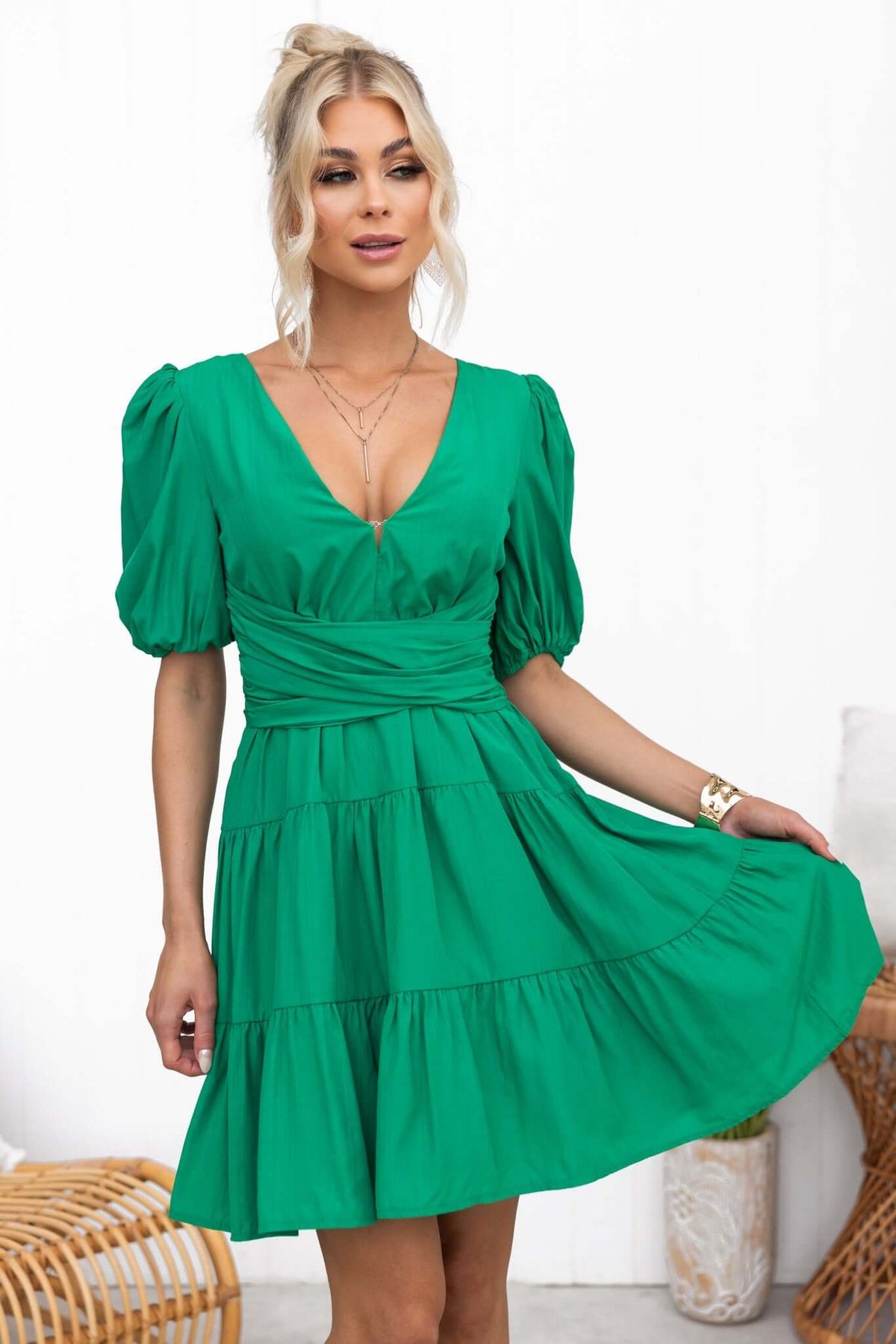 Model wearing a green Sakura Dress with a V-neckline and puff sleeves, showcasing a stylish flared design.