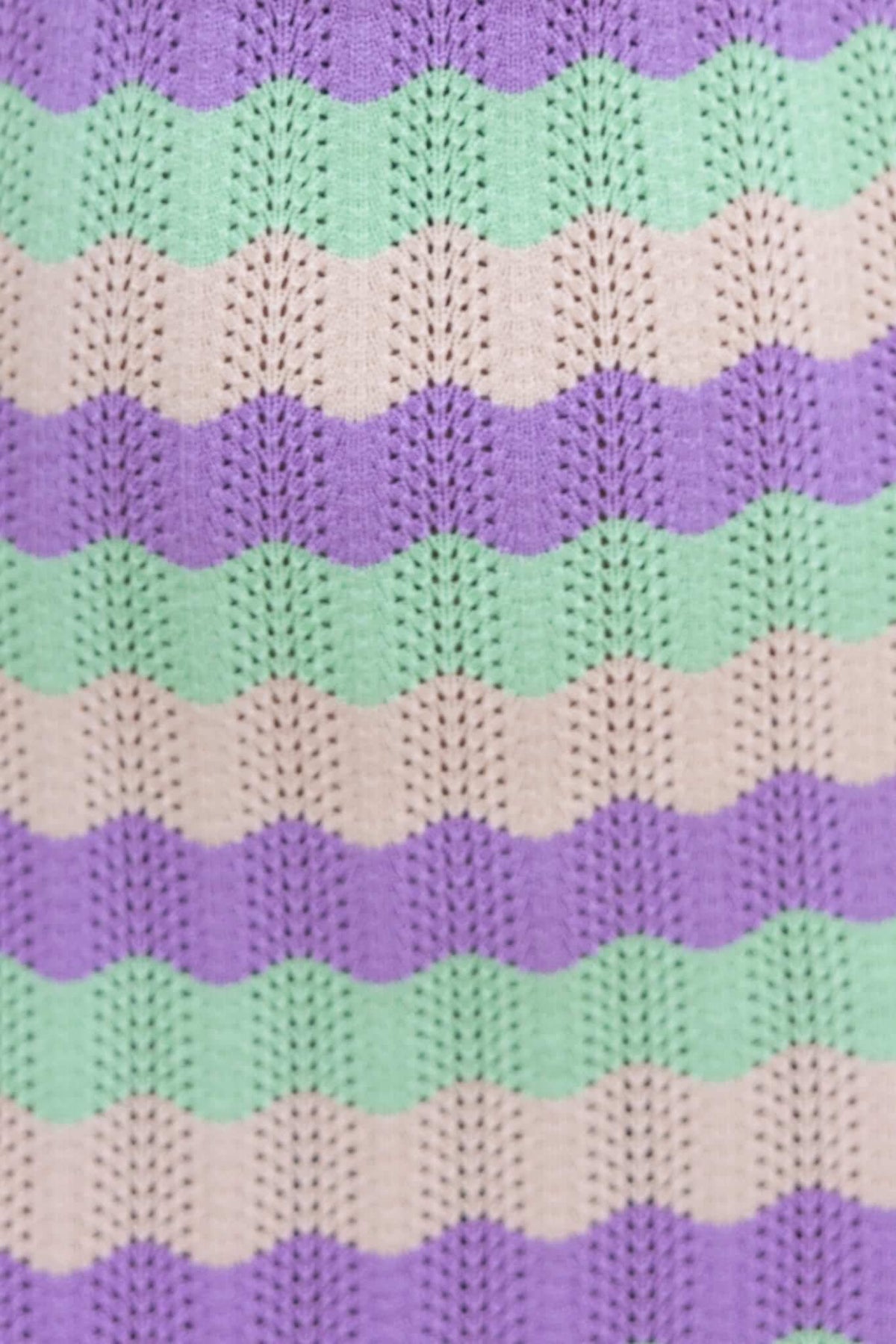Close-up of wave pattern knit fabric in purple, mint, and beige colors, showcasing unique texture and design.