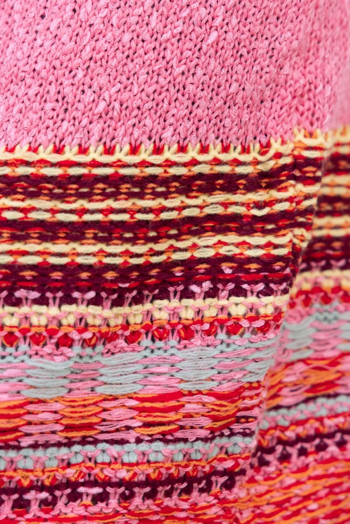 Close-up of colorful knit fabric featuring pink and multicolored striped patterns, showcasing the texture of the Lewis Cardigan.