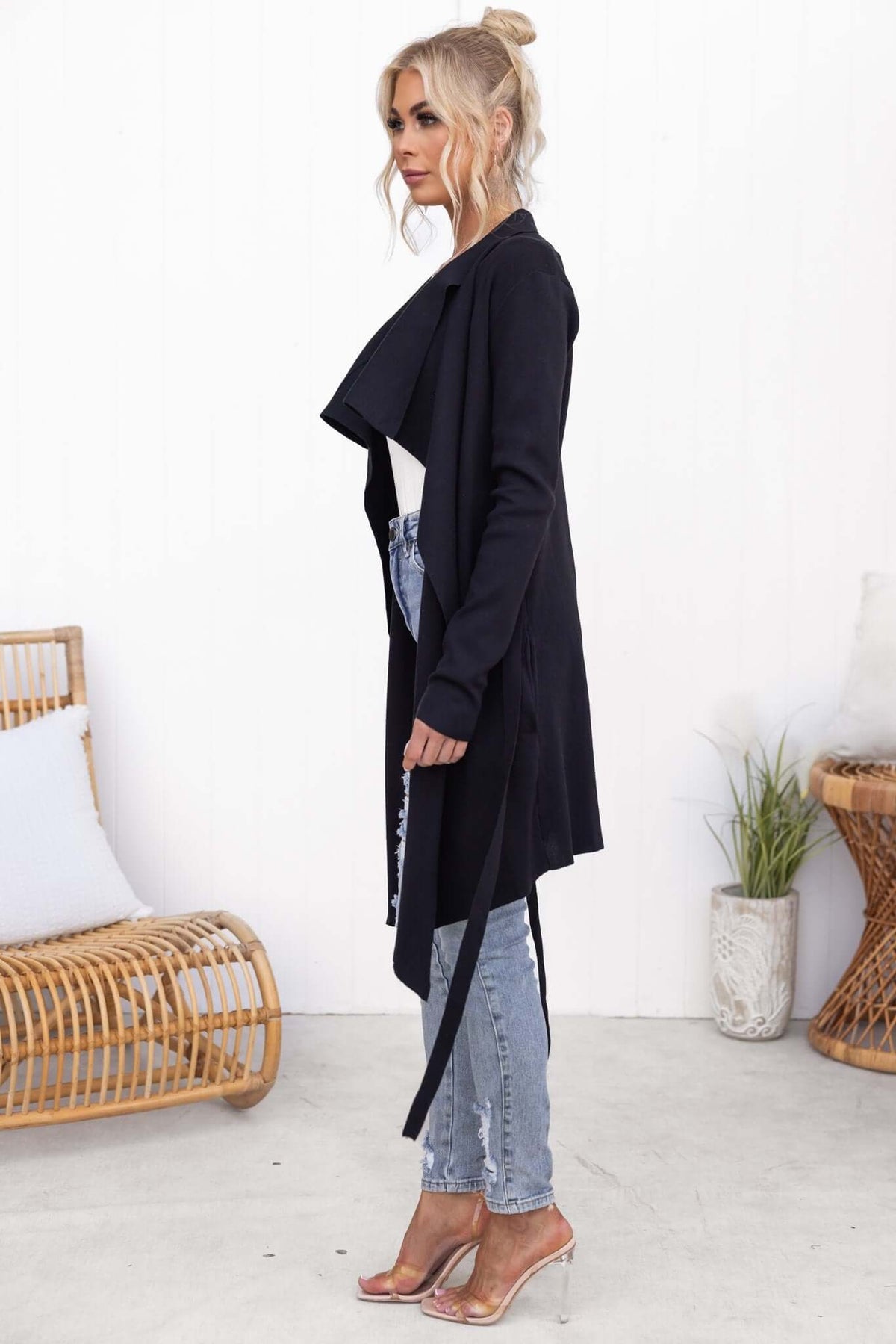Model wearing Acaia Cardigan in black ribbed knit with pockets and attached belt, styled with distressed jeans.