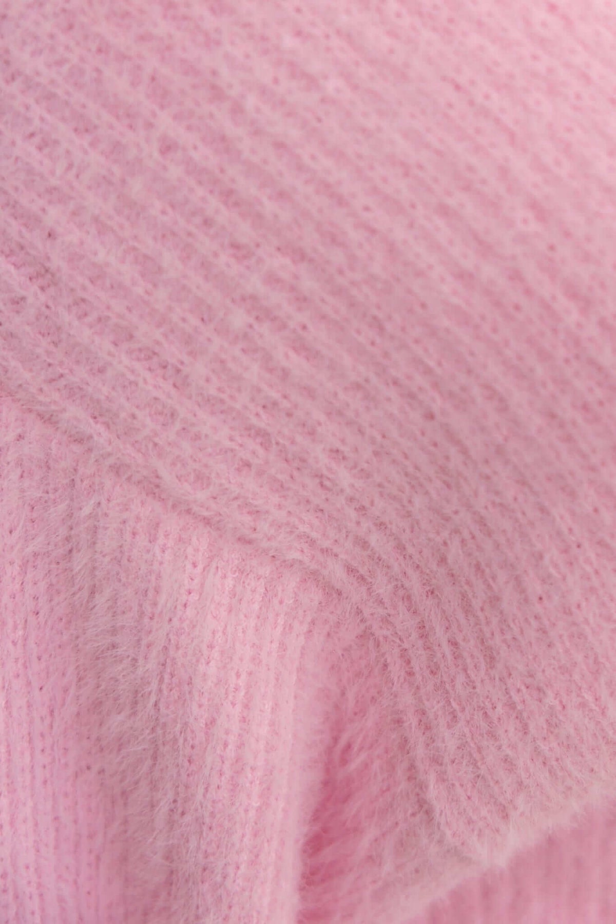 Close-up of fluffy pink knit fabric from a longline Shai Cardigan, showcasing its soft and stretchy texture.