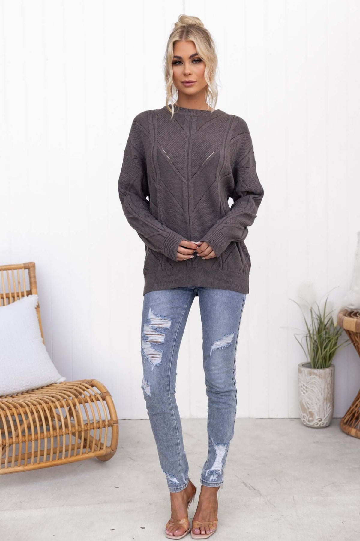 Model wearing Becker Jumper in grey, featuring a round neckline and cable knit style, paired with distressed jeans.