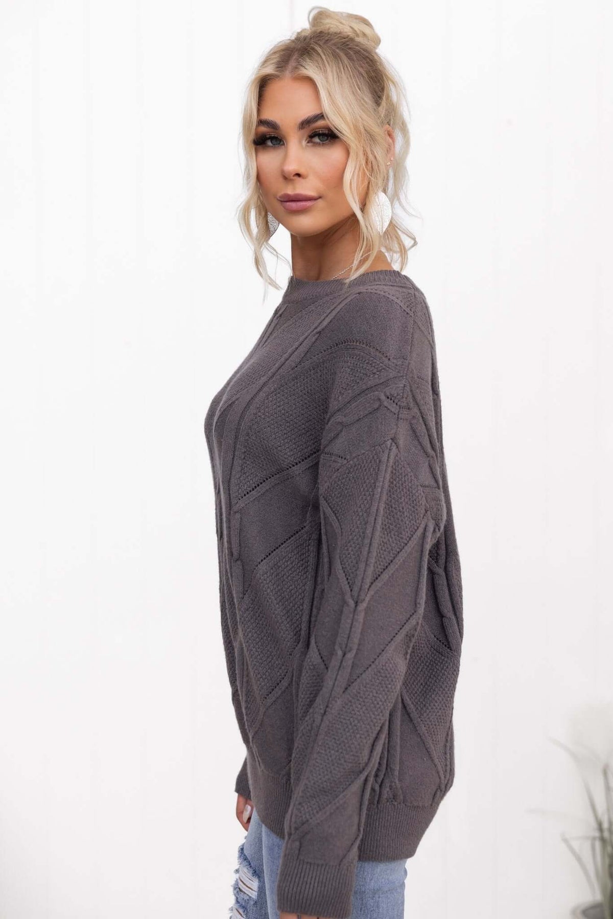 Becker Jumper in gray with round neckline and cable knit design, styled with casual ripped jeans.