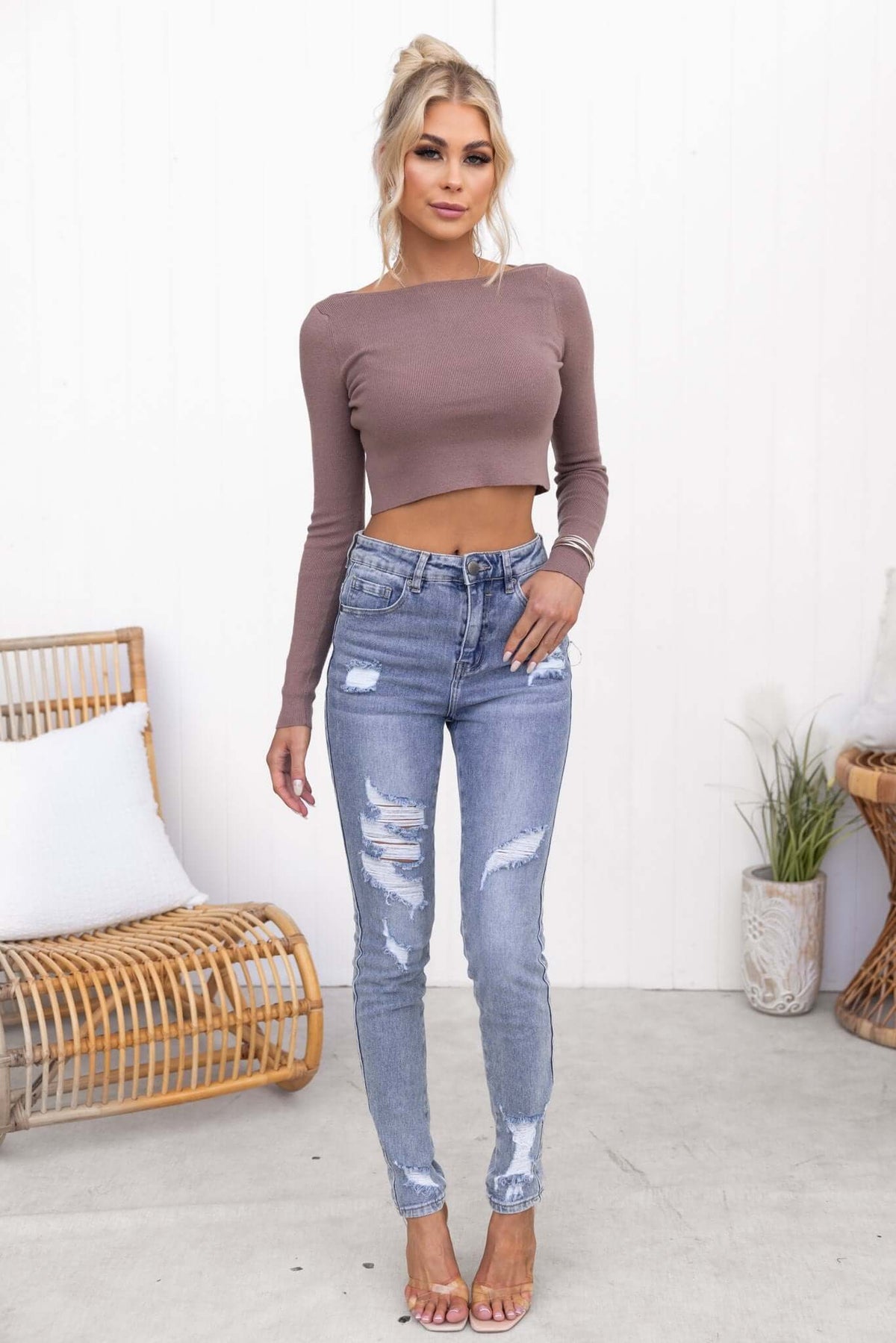 Model wearing a brown Derby Top with long sleeves, paired with distressed blue jeans and heeled sandals.