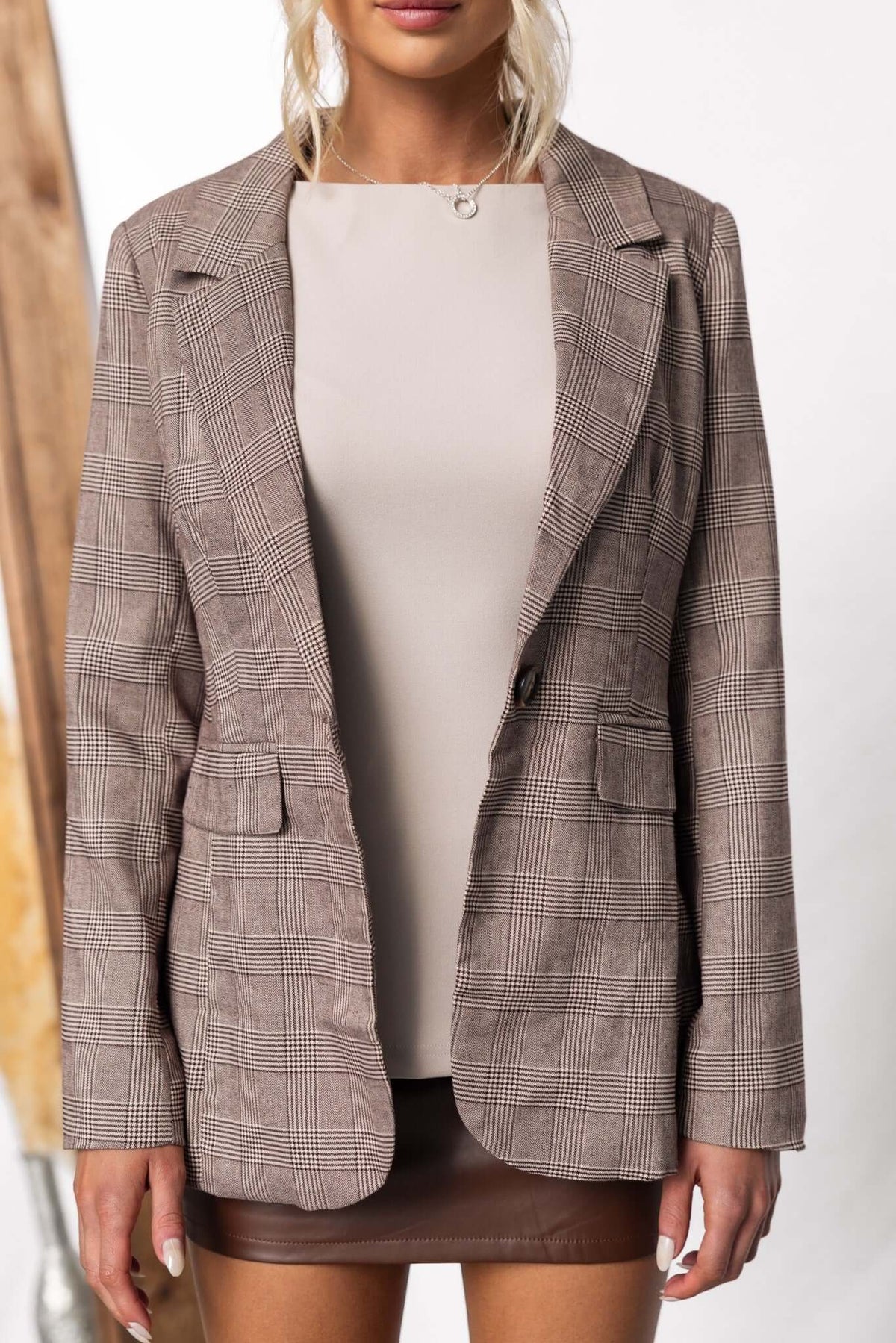 Ingrid Blazer with front pockets and shoulder pads, styled over a beige top, ideal for chic office wear.