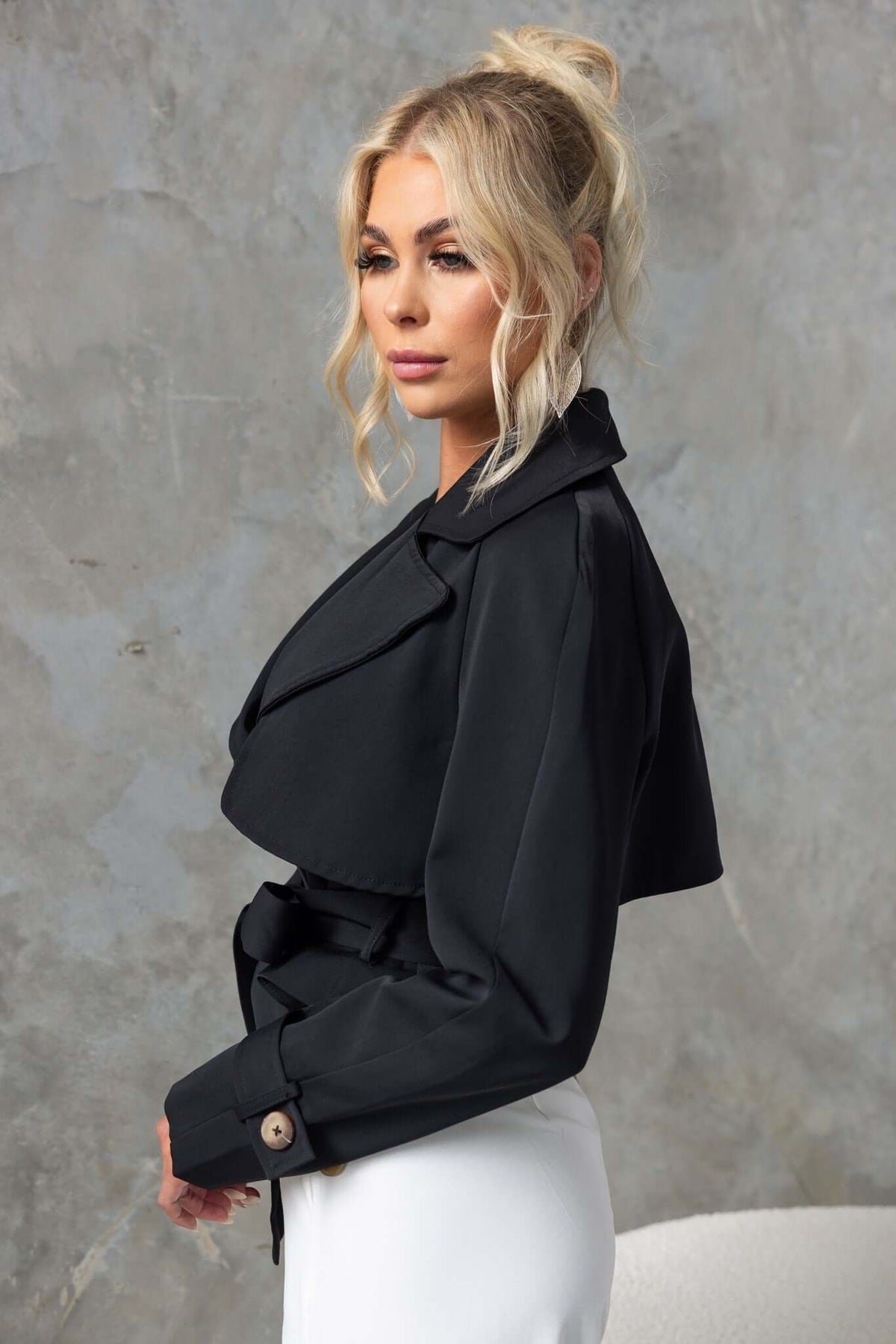 Model wearing the Ellis Coat, a stylish black trench with a cropped fit and removable tie.