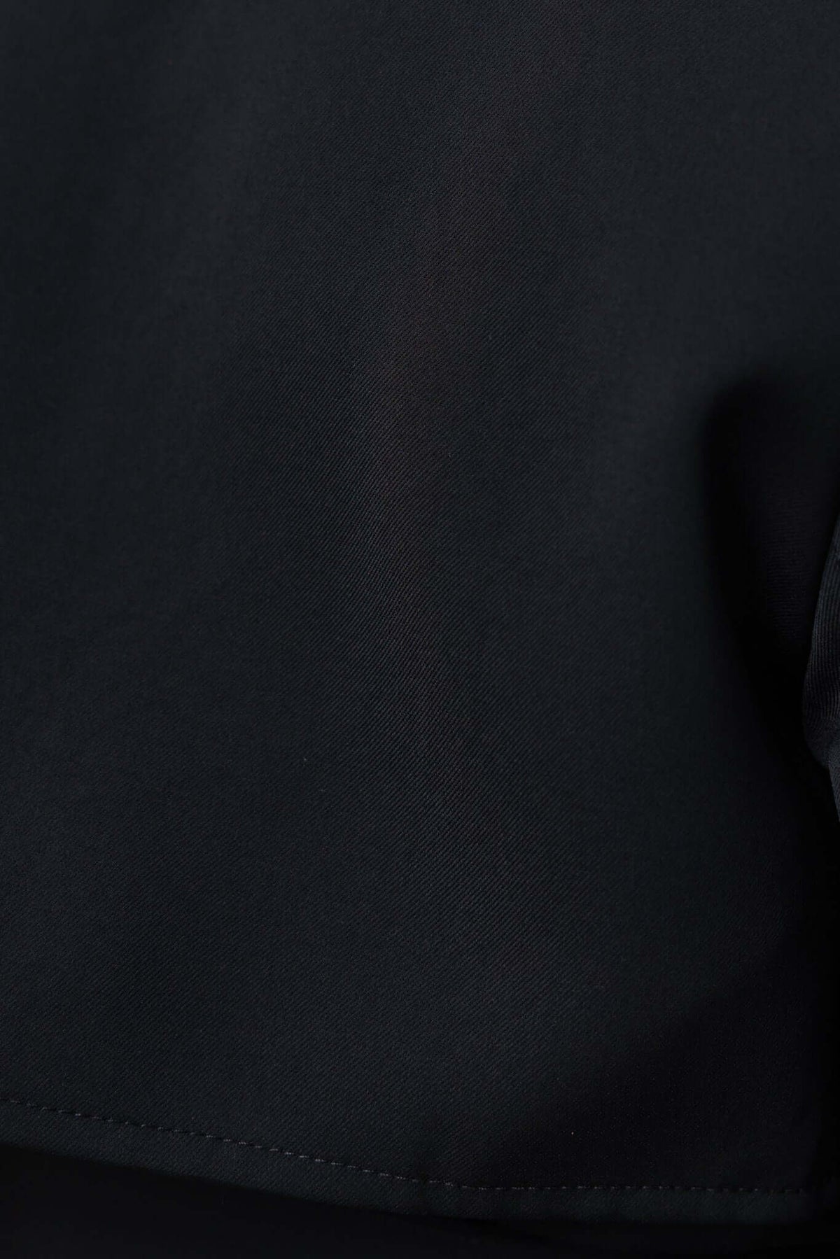 Close-up of the black Ellis Coat fabric showcasing its sleek, non-stretch material and clean lines.