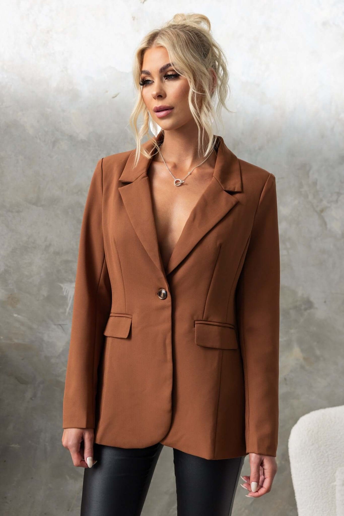 Desio Blazer in brown on model, featuring front pockets, shoulder pads, and a stylish split back.
