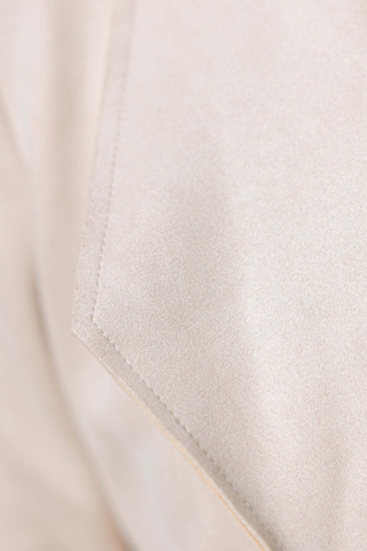 Close-up of beige fabric with lapel detailing from the Hayley Coat, showcasing a smooth, semi-light texture.