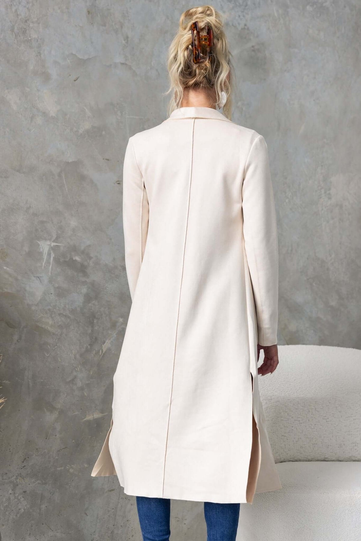 Back view of the Hayley Coat with draping lapel, high slits, and raw-cut edging in light fabric.