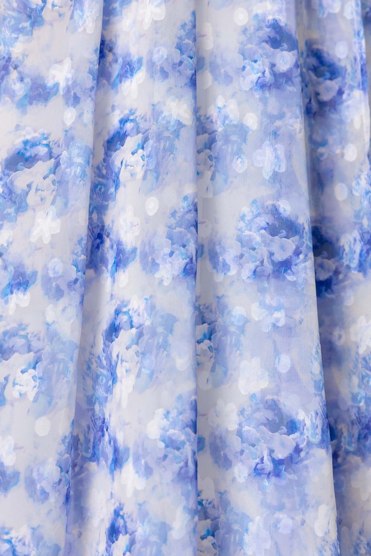 Close-up of soft chiffon fabric featuring a blue floral print with delicate polka dots.