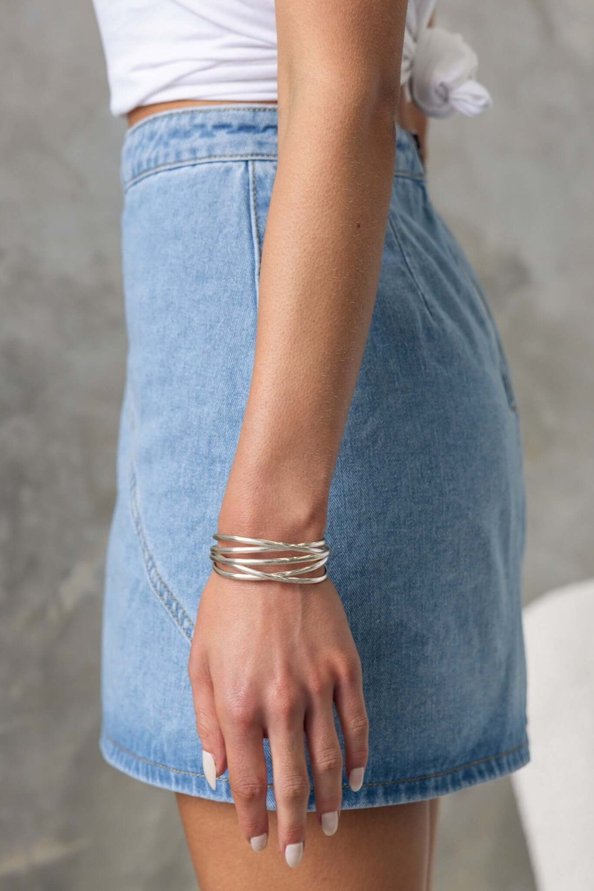 Side view of a woman wearing the Lizzie Denim Skirt, showcasing a mid-high waist and stylish denim design.