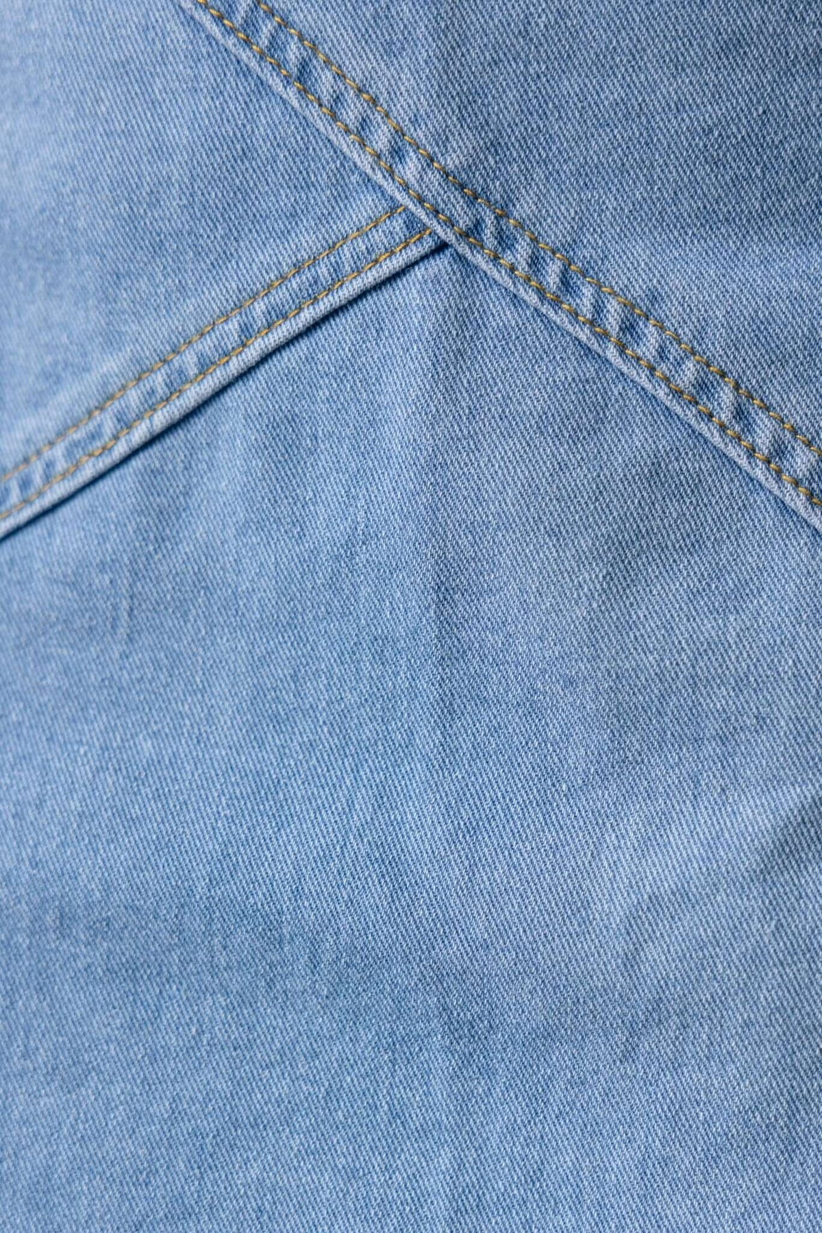 Close-up view of light blue denim fabric showcasing stitching details of the Lizzie Denim Skirt.