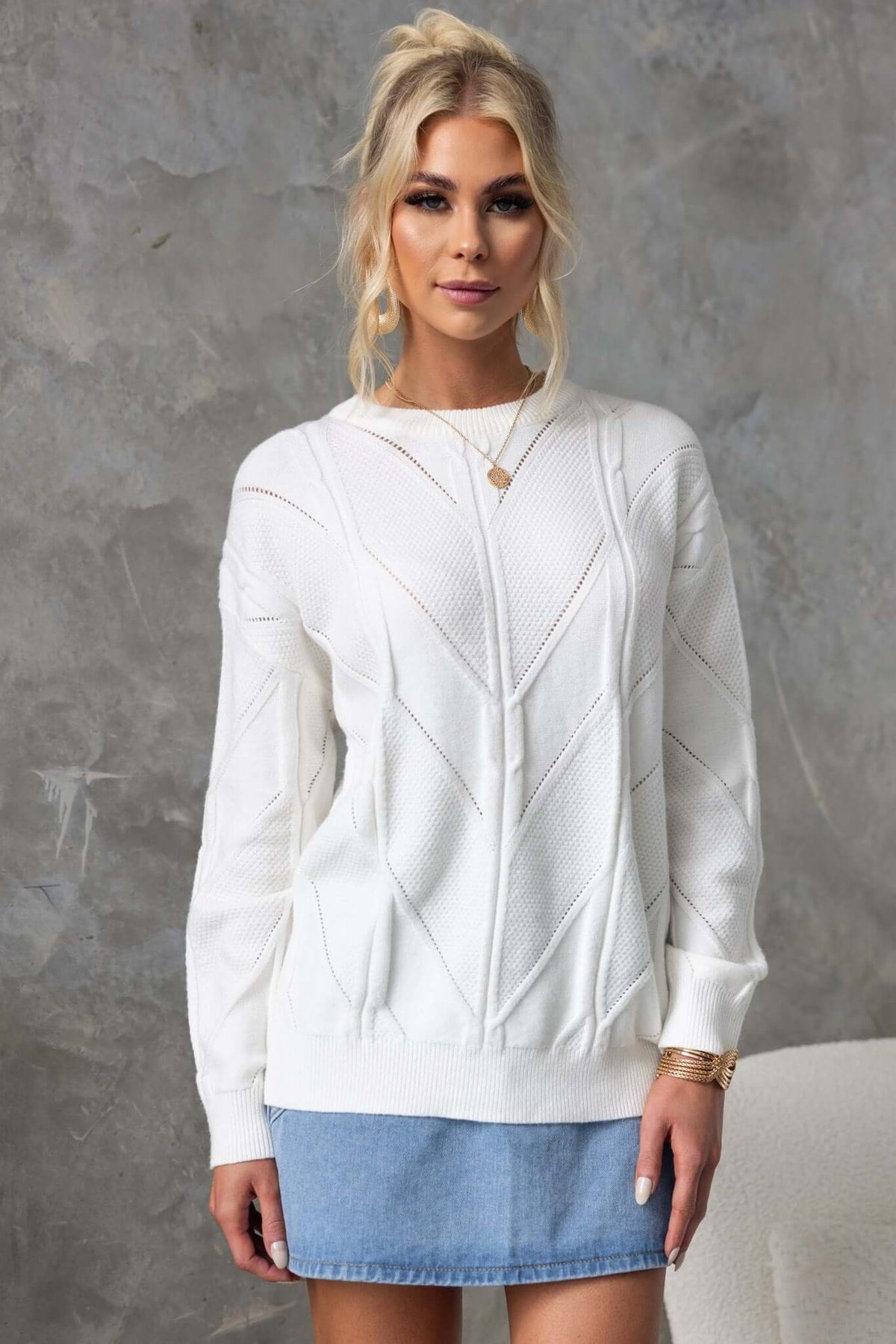 Becker Jumper in white, featuring a round neckline and cable knit design, styled with a denim skirt.