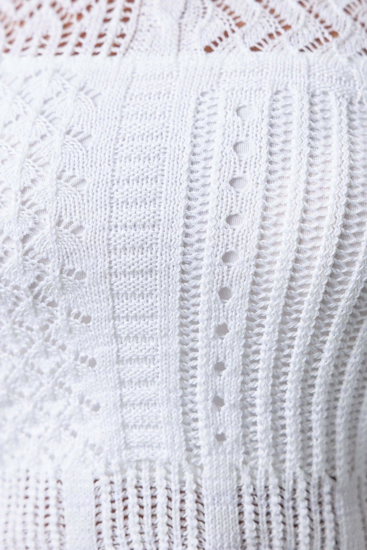 Close-up of textured white Perilla Top showcasing intricate knit patterns and lightweight fabric design.
