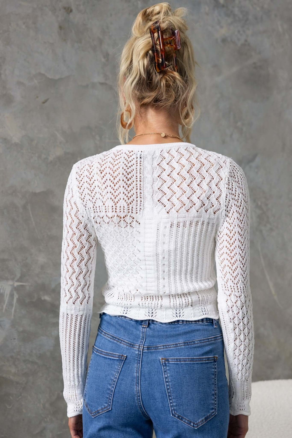 Back view of a Perilla Top featuring a round neckline and knit design, paired with high-waisted jeans.