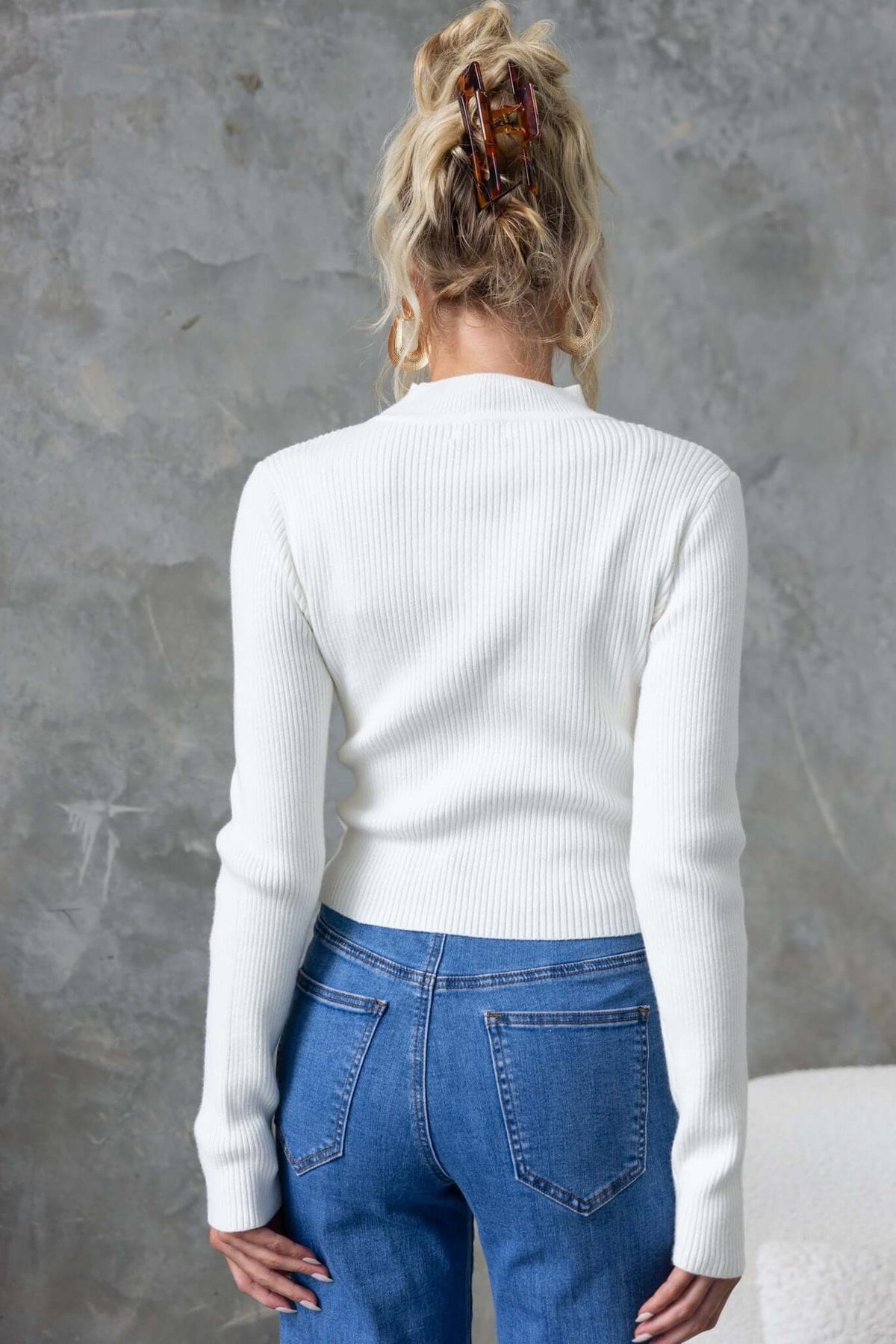 Back view of a model wearing a ribbed white Inala Top paired with blue jeans, showcasing its fit and style.