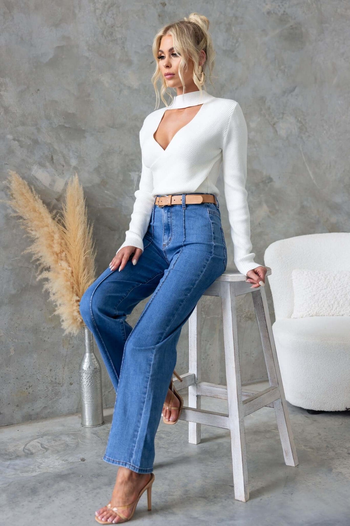 Model wearing Daffy Jeans with mid-high waist and wide legs, styled with a chic white top and a stylish belt.