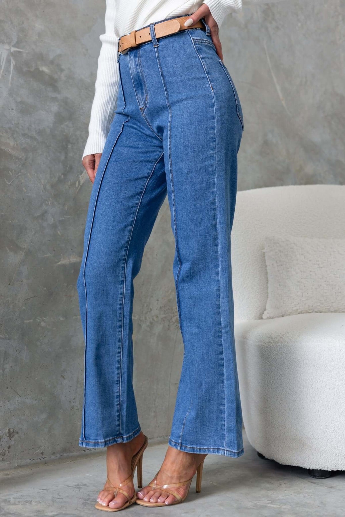 Daffy Jeans: Mid-high waist denim with wide legs, elastic waistband, and pockets, styled with a belt.