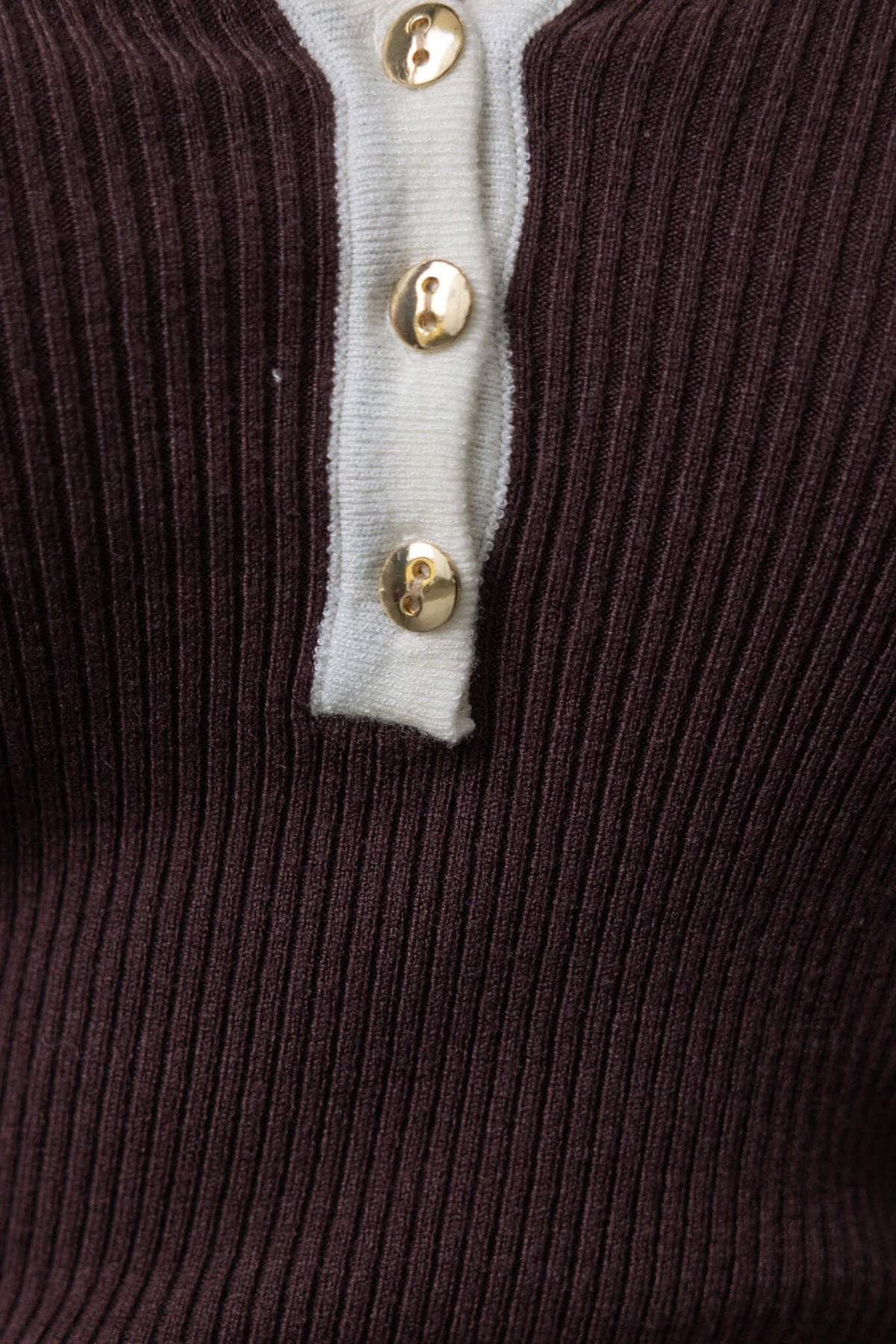 Close-up of Brydie Top featuring dark ribbed knit fabric and button-up front with contrasting neckline.
