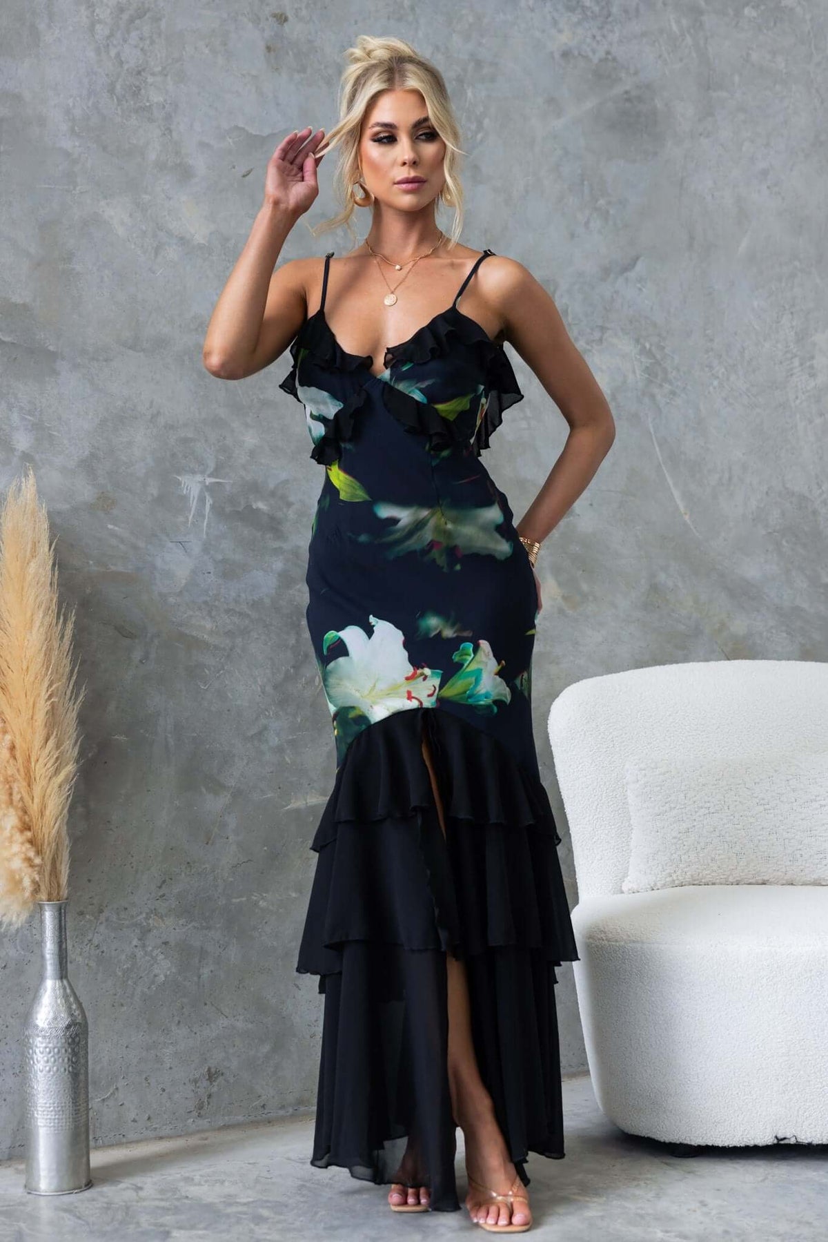 Elegant black maxi dress with floral print, ruffles, adjustable straps, and front split, perfect for special occasions.