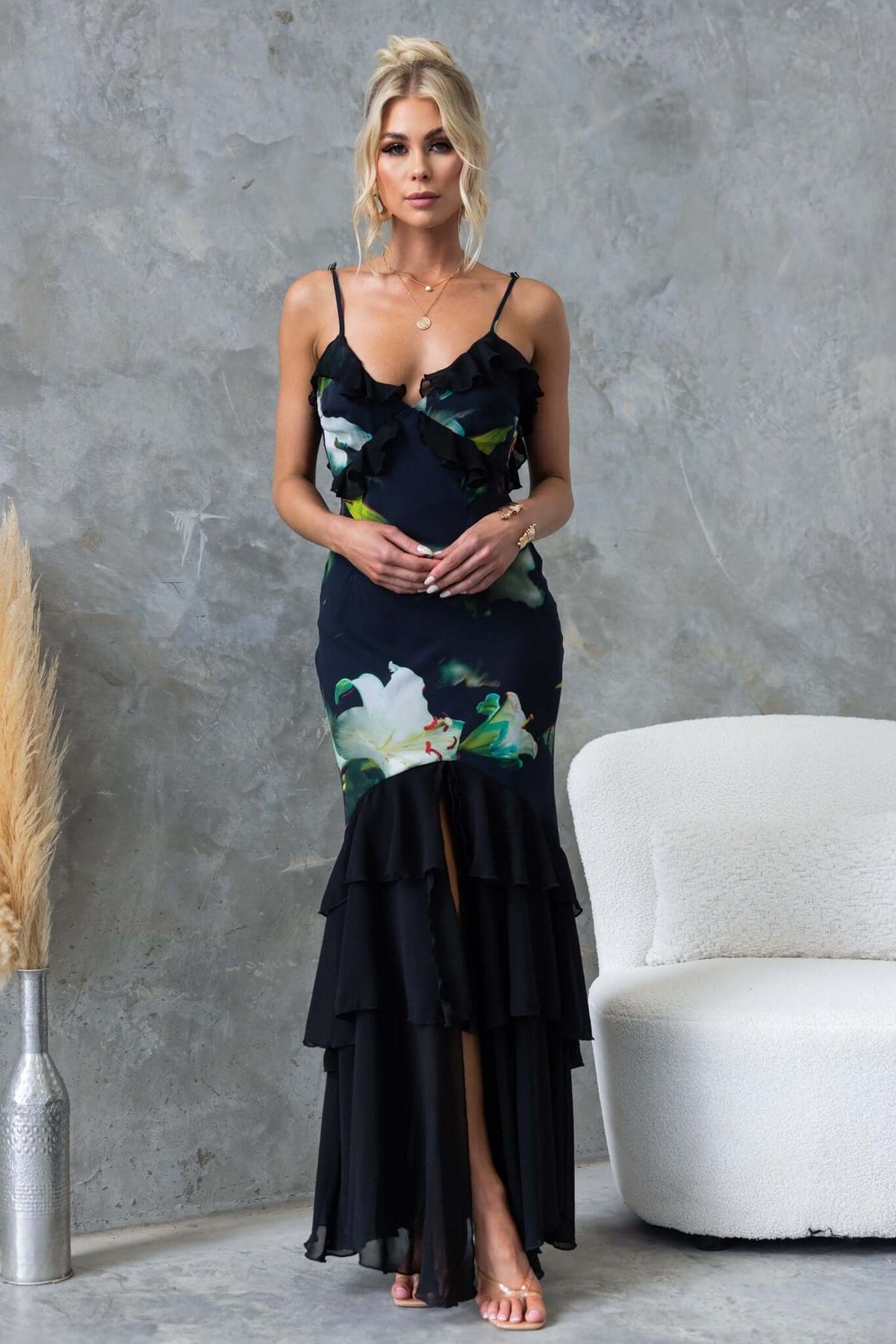 Elegant black maxi dress with floral design, adjustable straps, front split, and ruffles, perfect for special occasions.