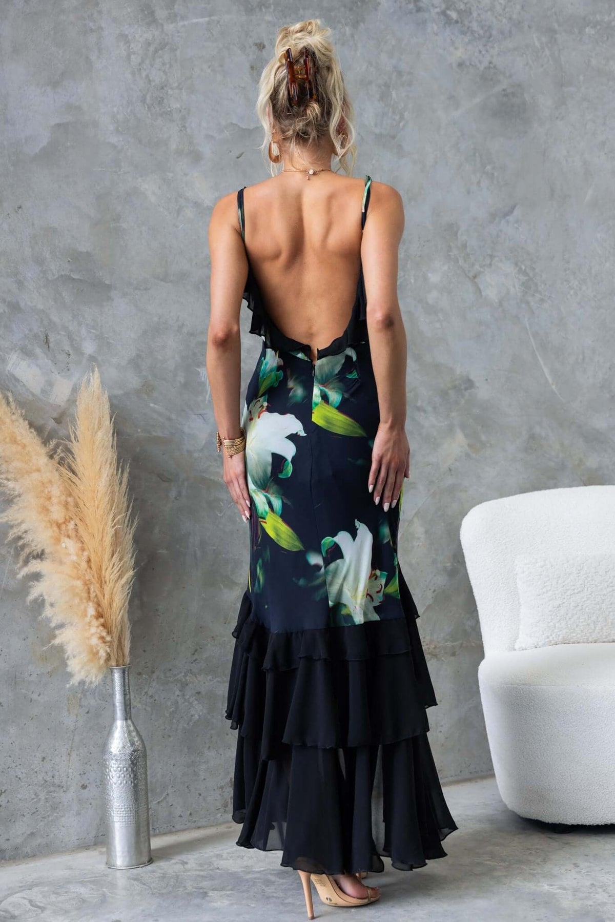 Elegant back view of a black floral maxi dress with ruffles and adjustable straps.