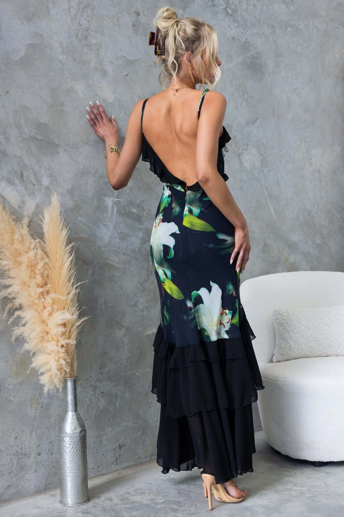 Elegant black maxi dress with floral design, adjustable straps, and ruffled layers, showcased in a stylish setting.