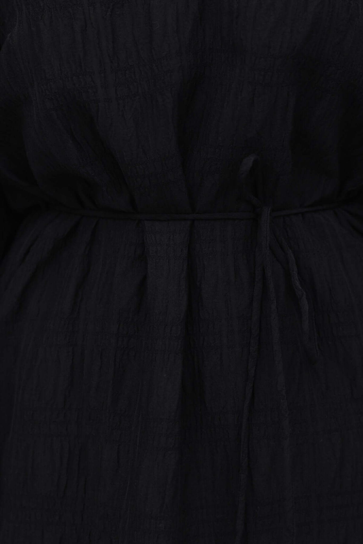 Close-up of the textured black Davis Dress featuring a removable tie at the waist and elastic sleeves.