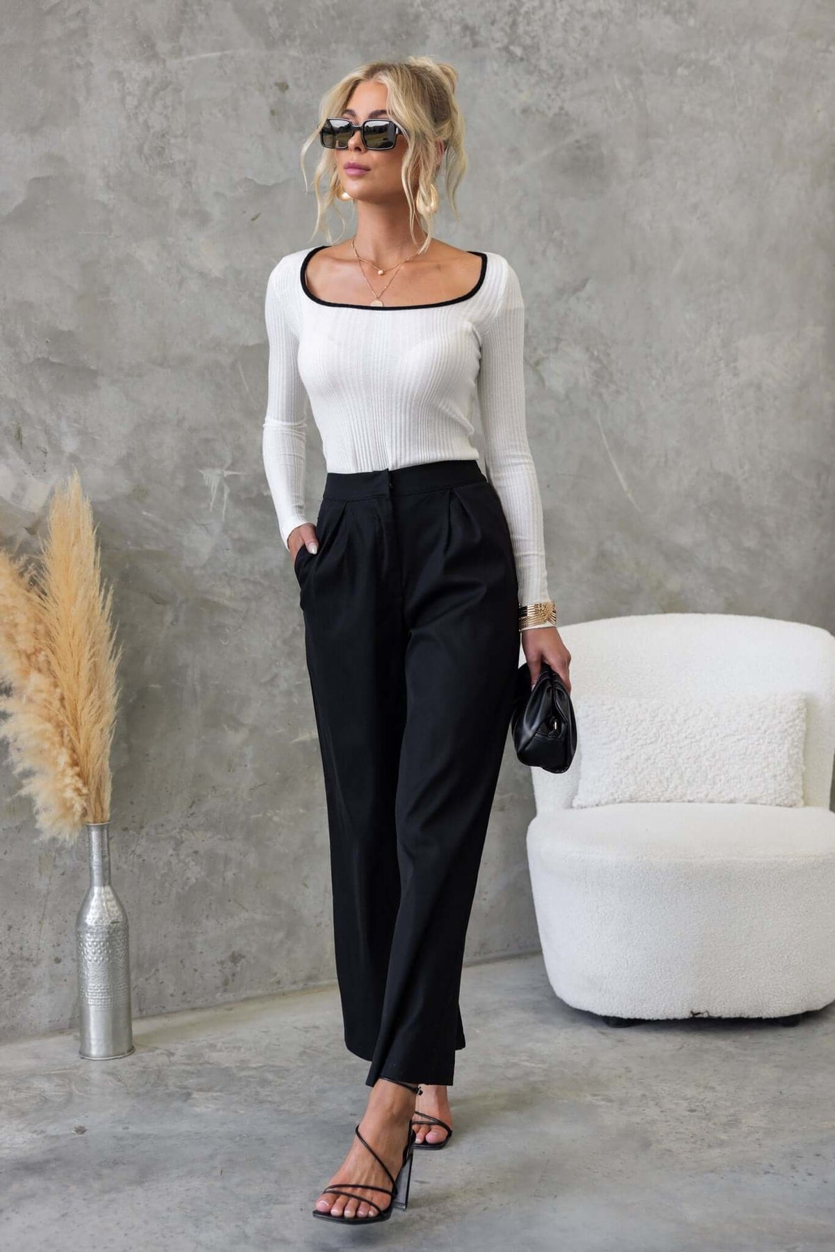 Stylish woman in Rayna Top, round neckline, paired with high-waisted black trousers and chic accessories.