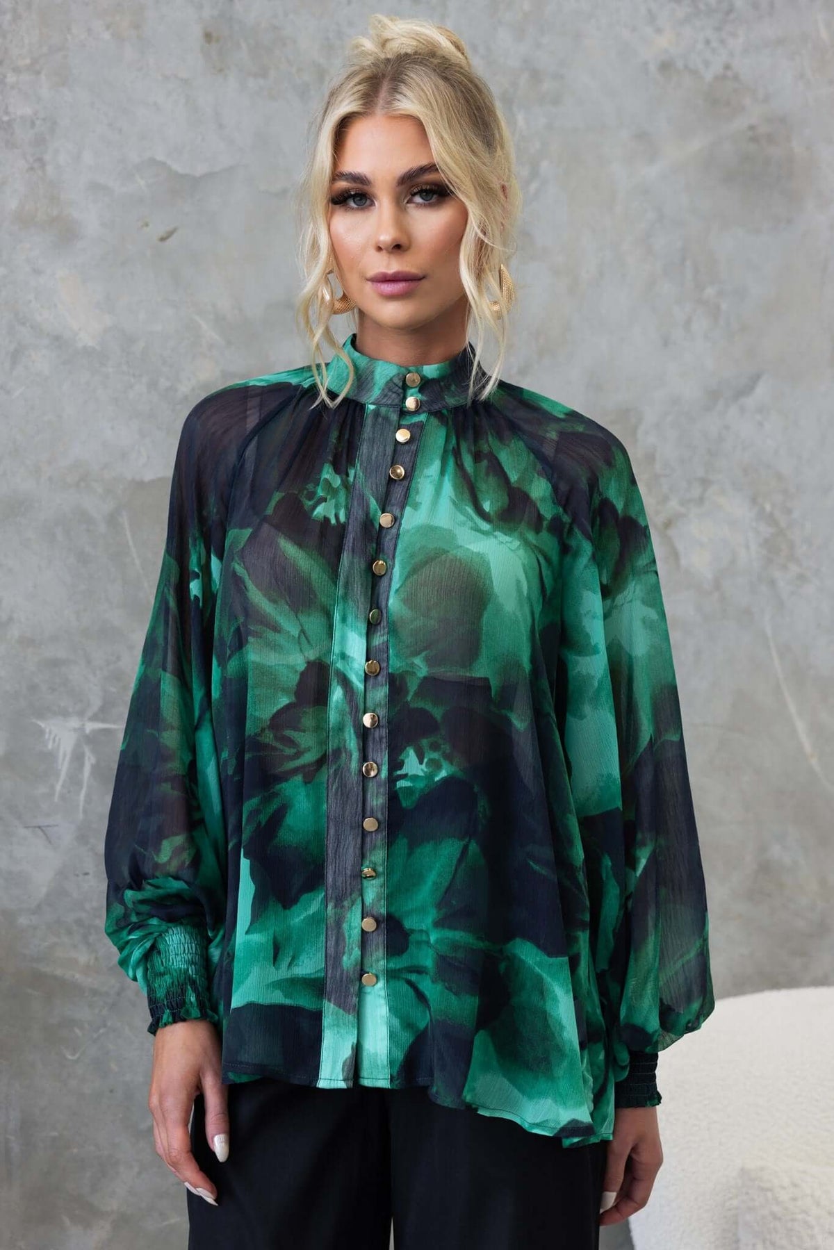 Orazio Top featuring a high neckline, button-up front, and floral chiffon material, styled casually with relaxed fit.