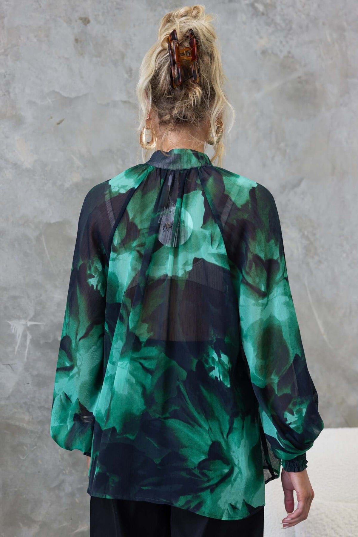 Model wearing Orazio Top, showcasing its high neckline and floral chiffon design from the back view.