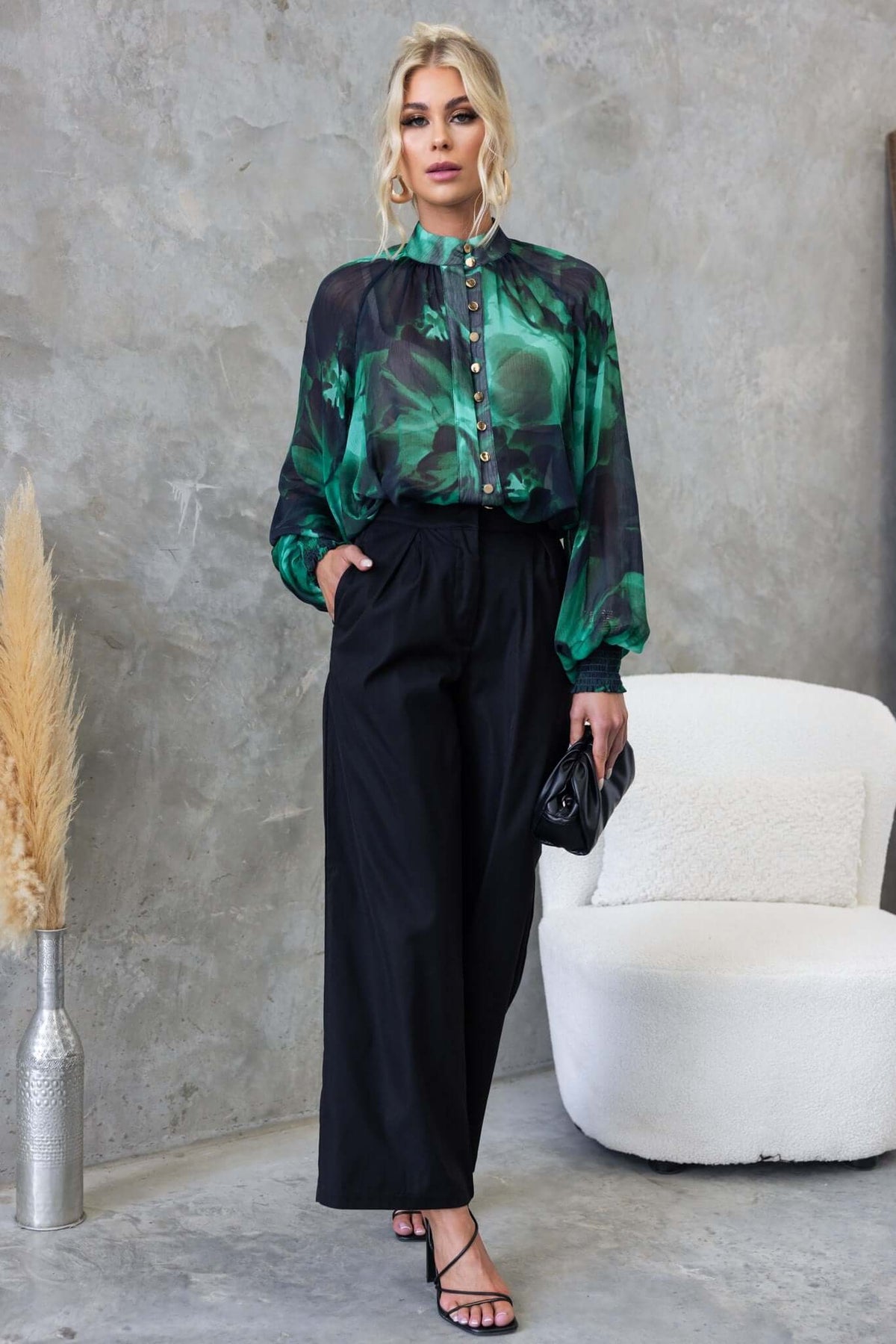 Model wearing Orazio Top in chiffon with high neckline and button-up front, paired with black trousers.