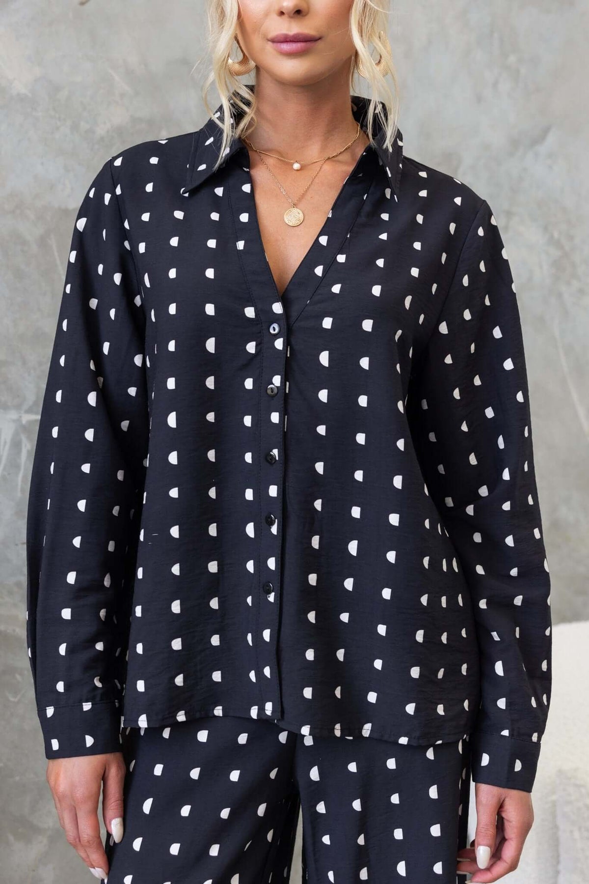 Black button-up Marion Shirt with textured pattern, worn by woman with blonde hair, against a neutral background.