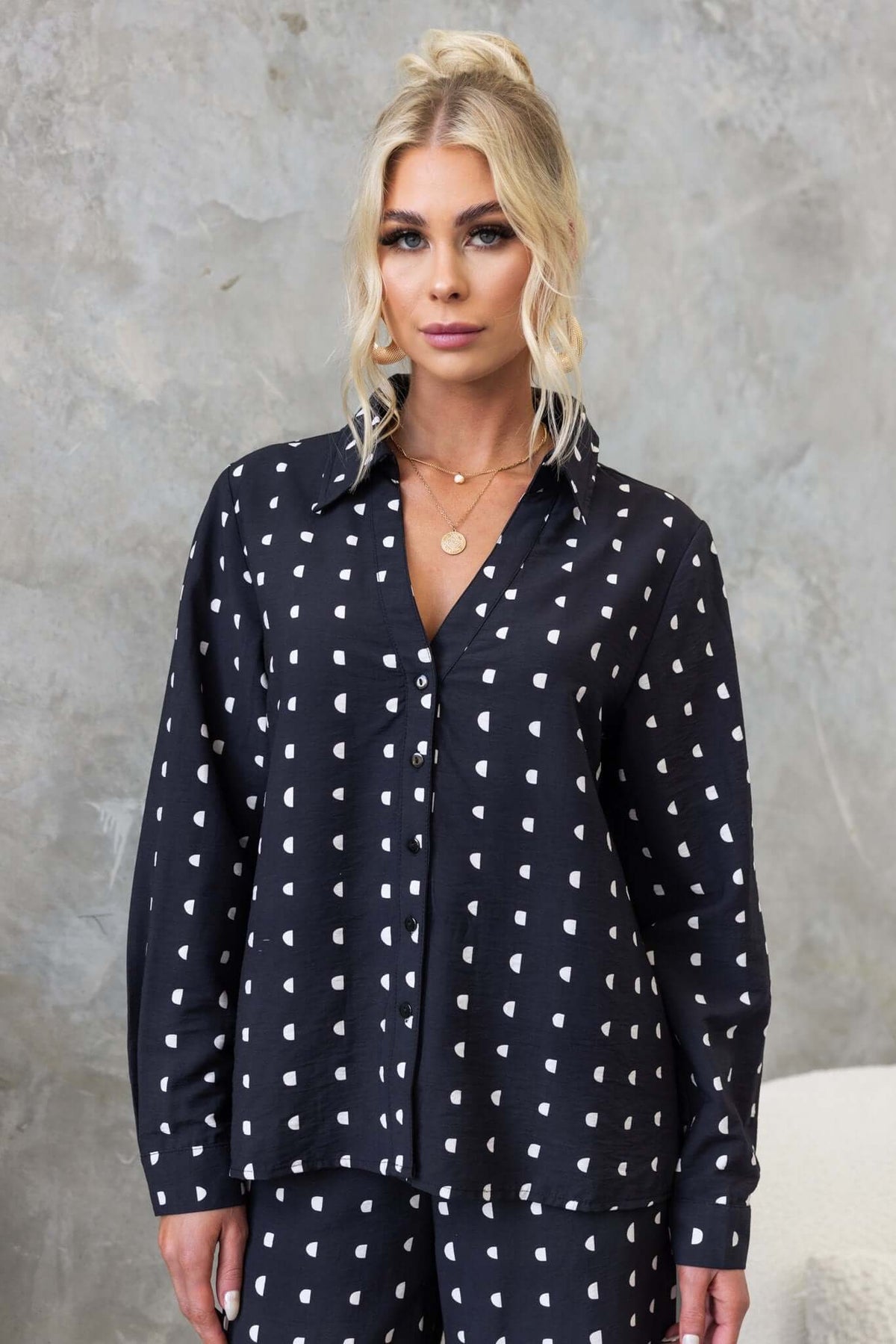 Model wearing a black Marion Shirt with white heart print, featuring a collar and button-up front.