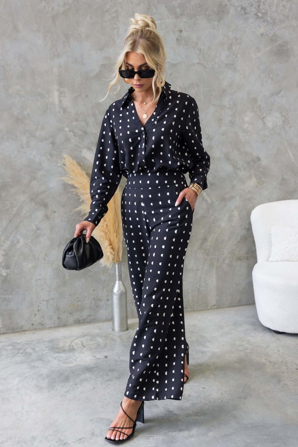 Model wearing stylish black Marion Pants with polka dots, mid-high waist, and trendy accessories in a modern setting.