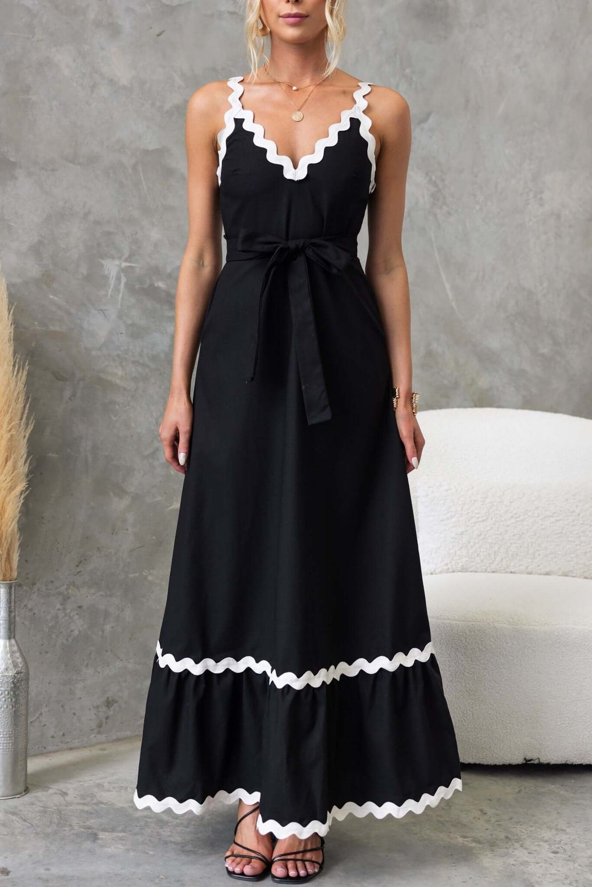 Black Thorelle maxi dress with V-neckline, white scalloped trim, removable tie, and side pockets.