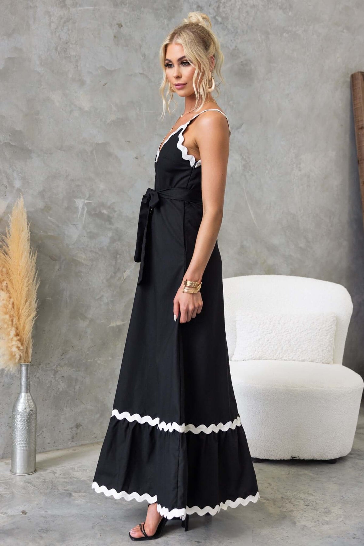 Model wearing Thorelle black maxi dress with V-neckline and removable tie, styled against a modern background.