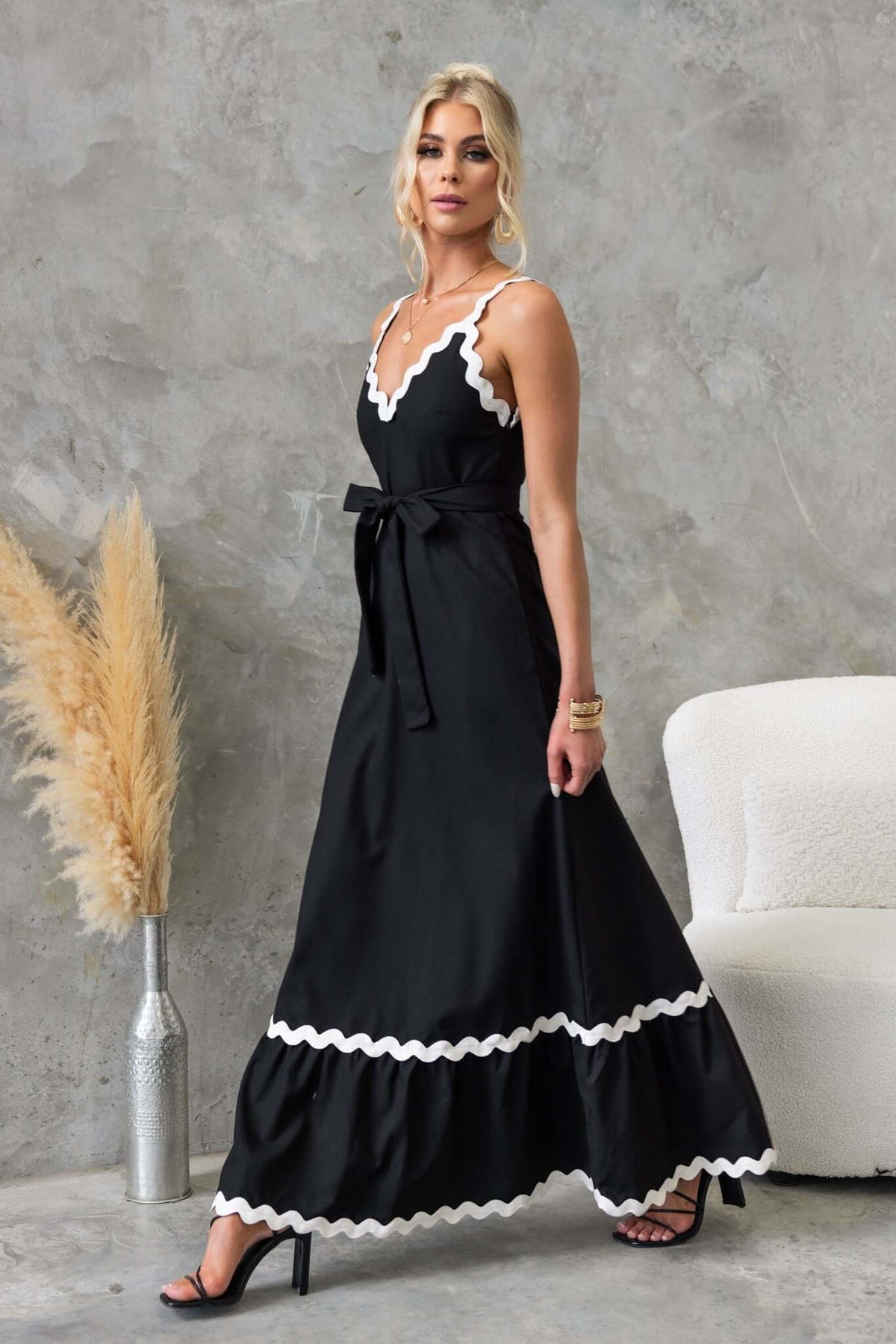 Elegant black Thorelle maxi dress with V-neck, removable tie, and white trim, styled with heels.