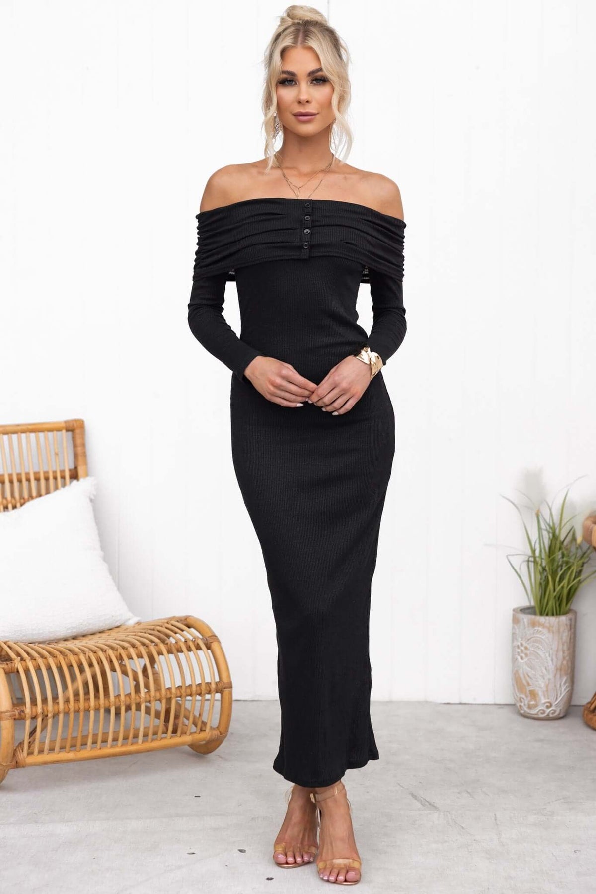 Black Judah Maxi Dress with off-shoulder neckline, faux buttons, and ribbed material, styled by model in a minimalist setting.