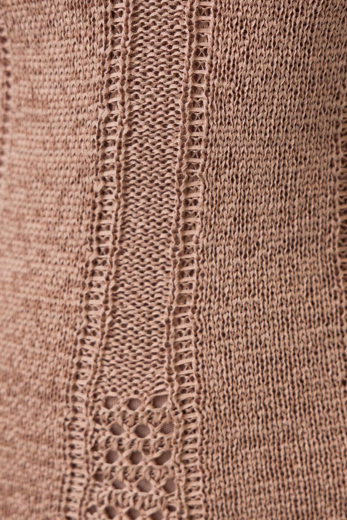 Close-up of textured knit fabric in a soft beige hue, showcasing intricate stitching details for stylish clothing.