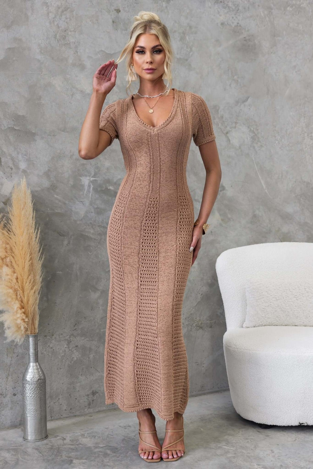 Qenna Maxi Dress in knit material with V-neckline, styled with beige strappy heels against a modern grey backdrop.