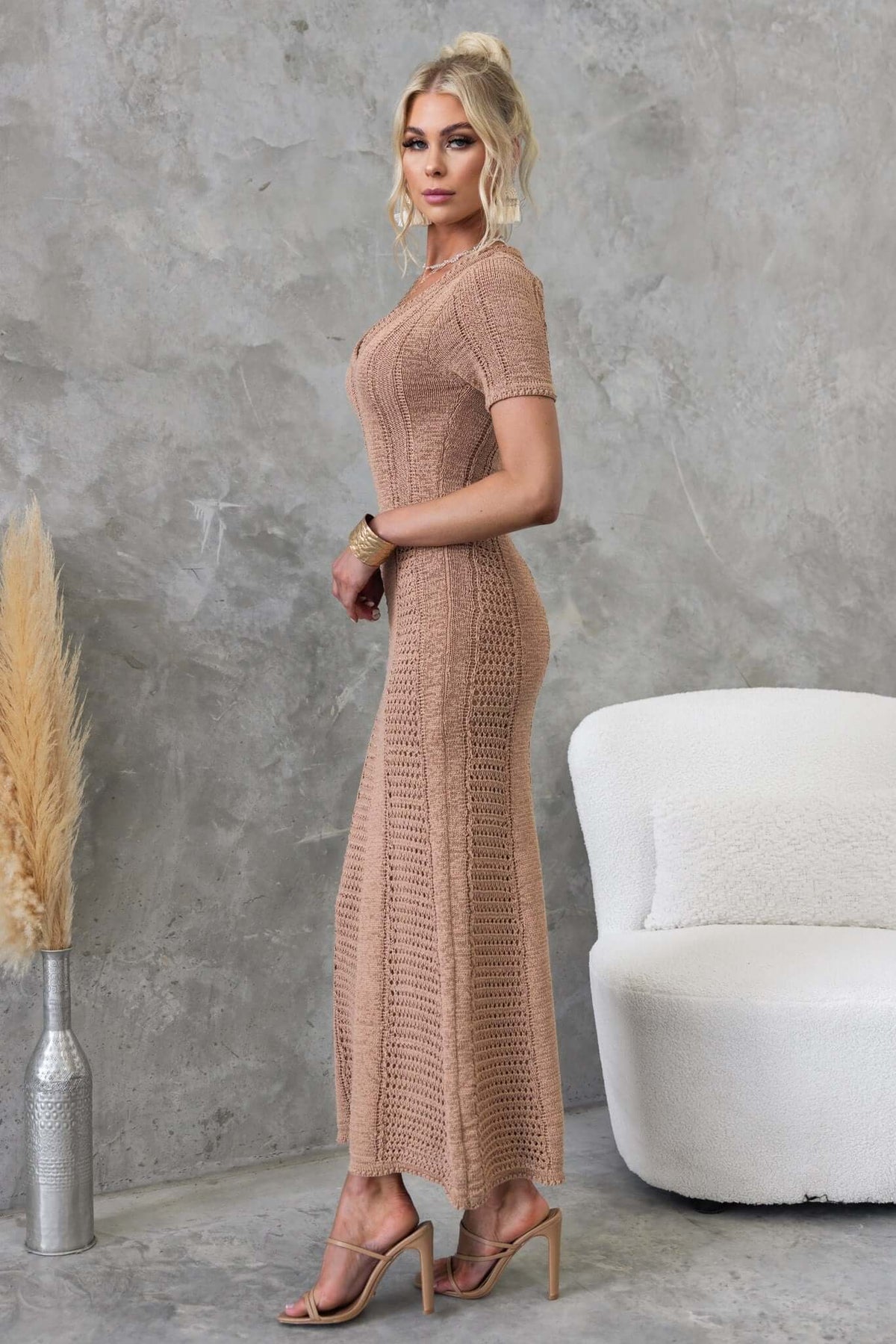 Model wearing Qenna Maxi Dress in knit material, showcasing V-neckline and firm stretch fit against a textured background.
