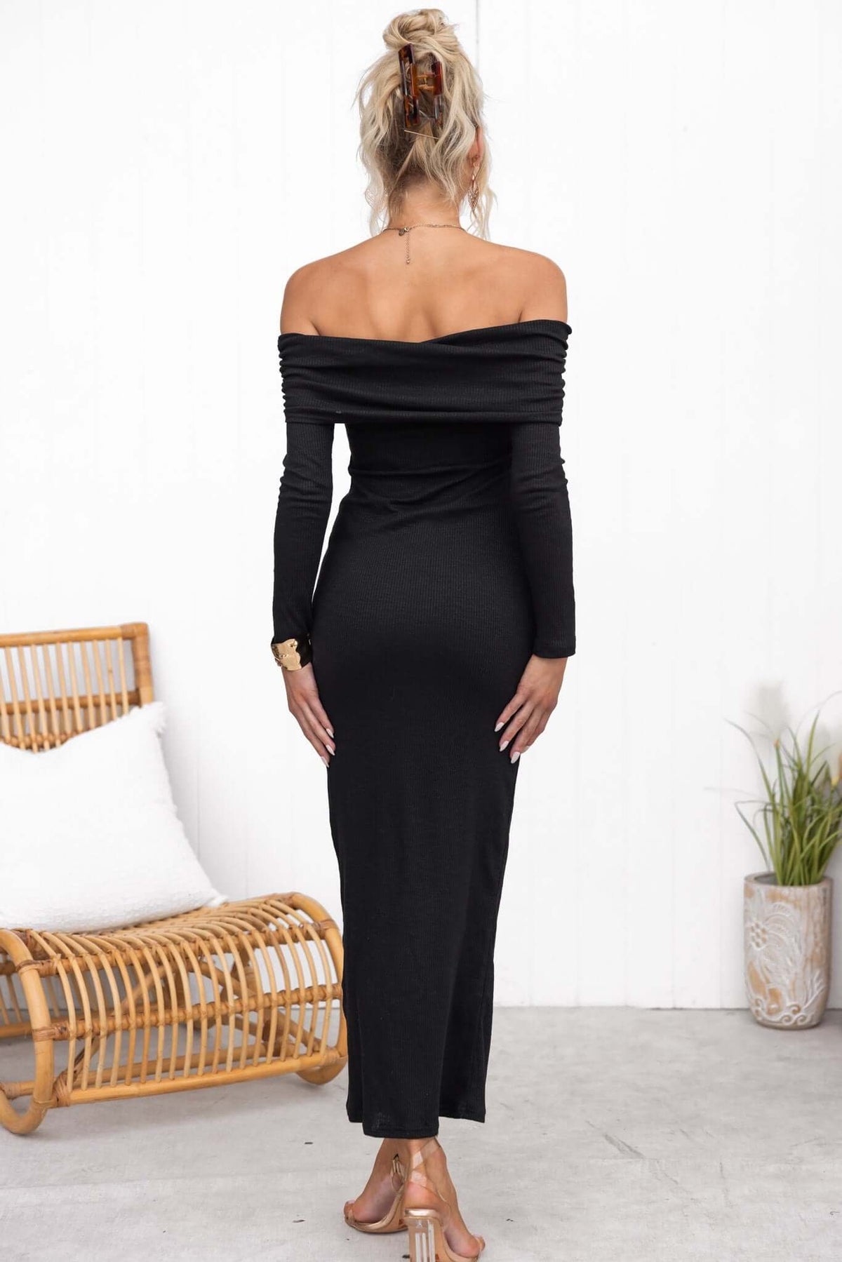 Model wearing a black off-shoulder maxi dress, showcasing ribbed material and a sleek fit.