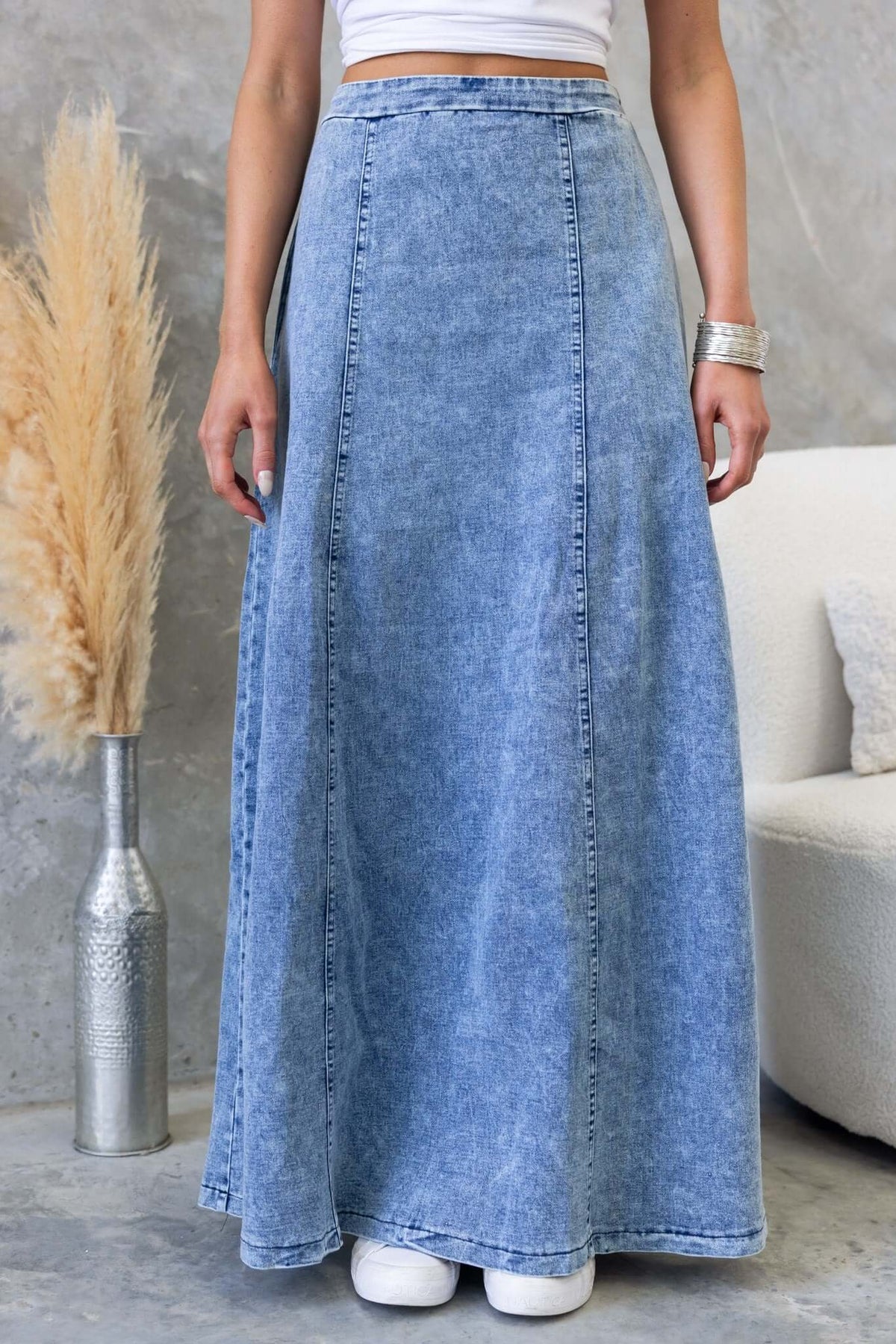 Denim maxi skirt with mid-high waist, two side pockets, and a flowy fit, styled with a simple white top.