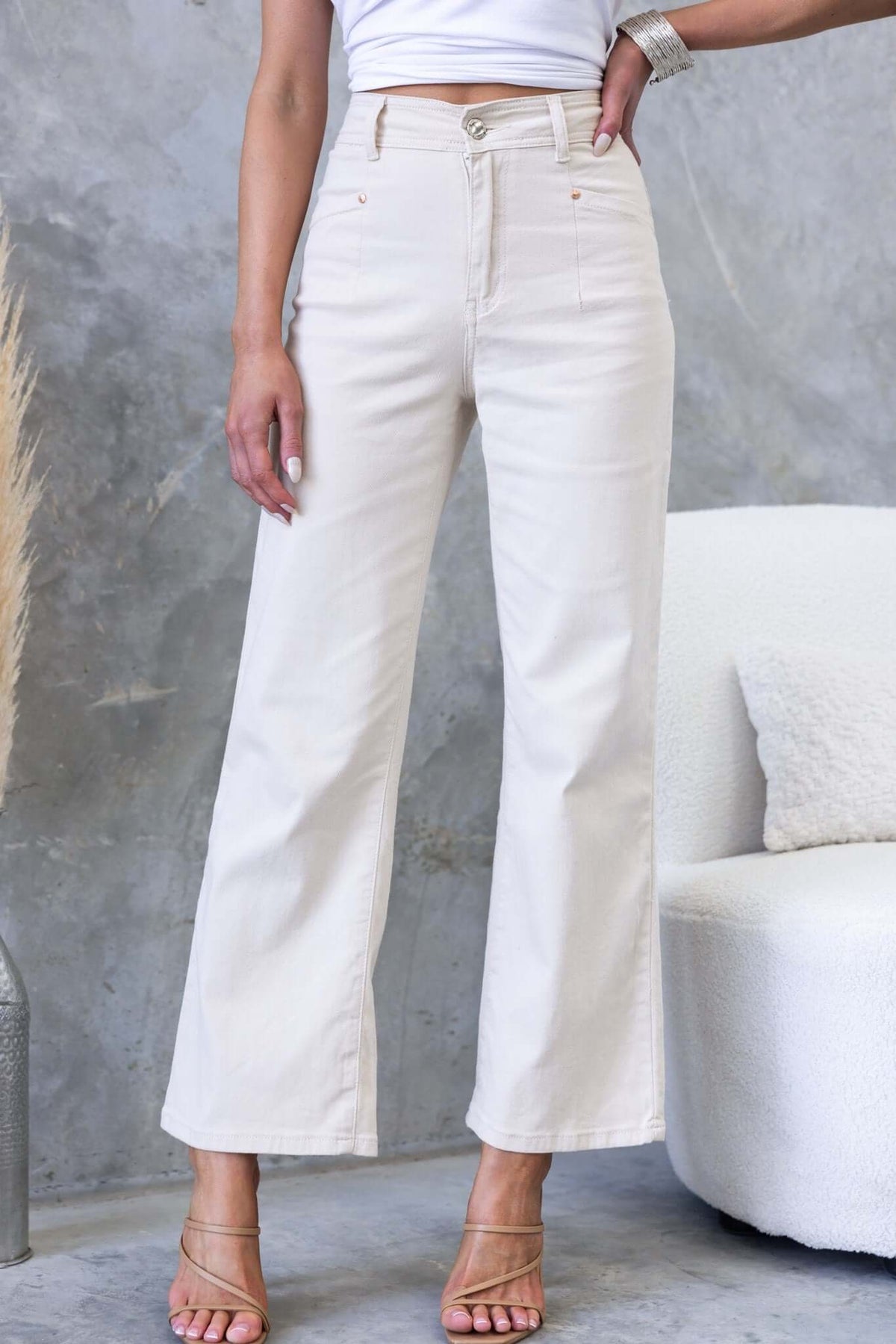 Blanca Jeans featuring mid-high waist, wide leg fit, and pockets, styled with trendy sandals against a minimalist backdrop.