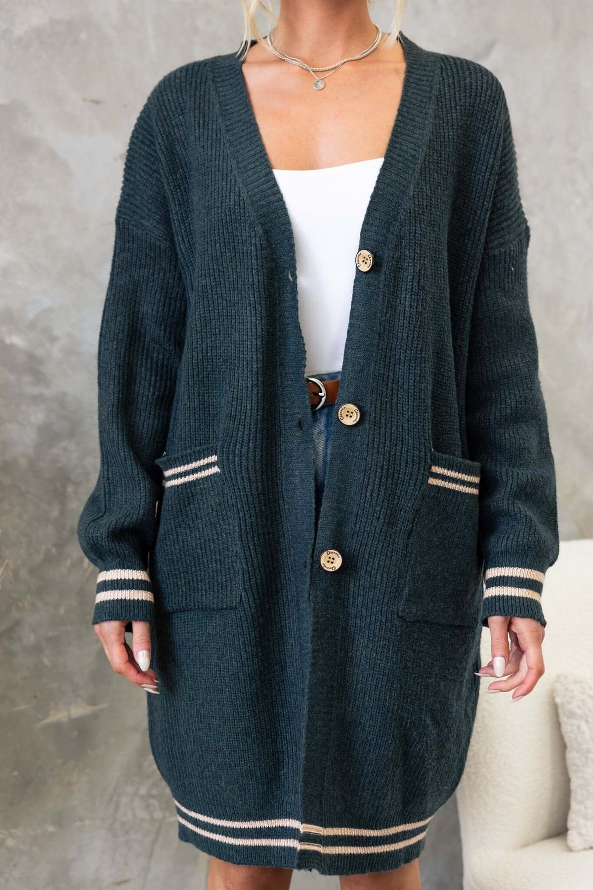 Dark green longline cardigan with V-neckline, button-up front, and pockets, made from stretchy knit material.