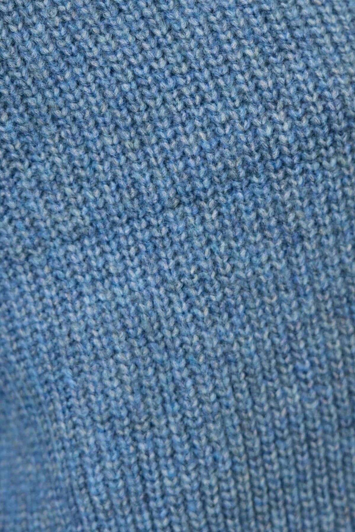 Close-up of the knit fabric texture of a light blue cardigan, showcasing its soft and stretchy acrylic material.